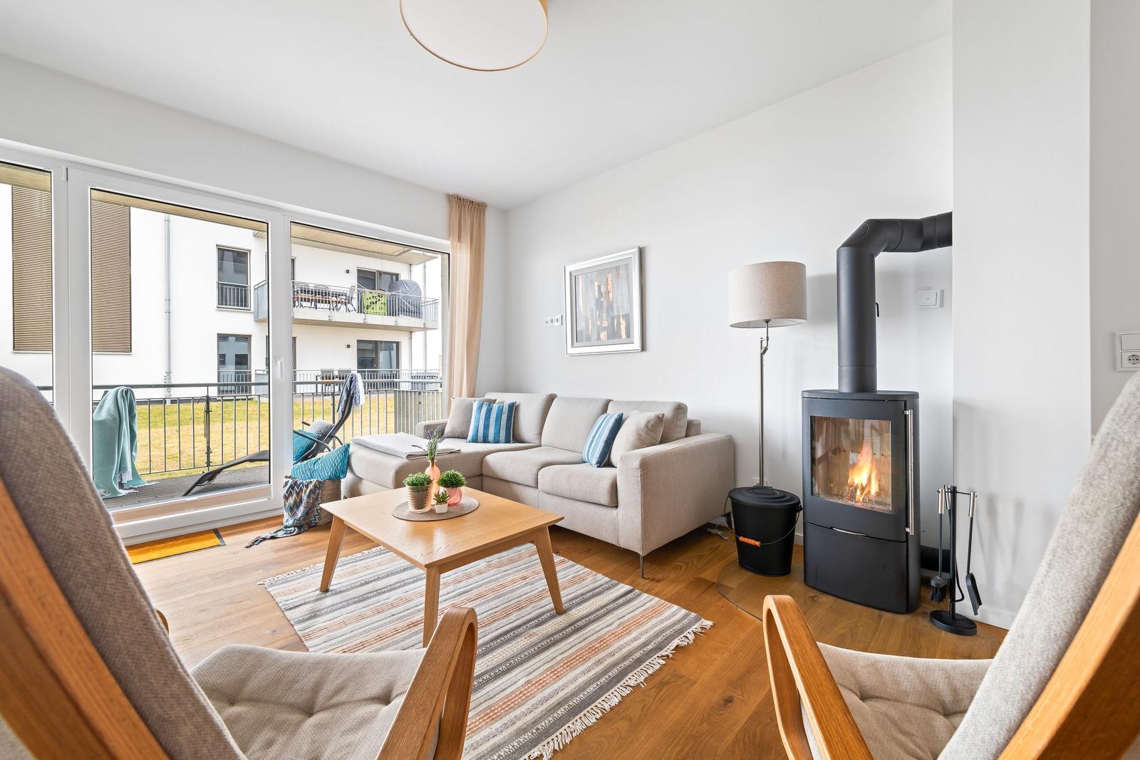 Wohnzimmer mit Sofa, Kamin und Balkon. Holzboden und modernes Mobiliar.