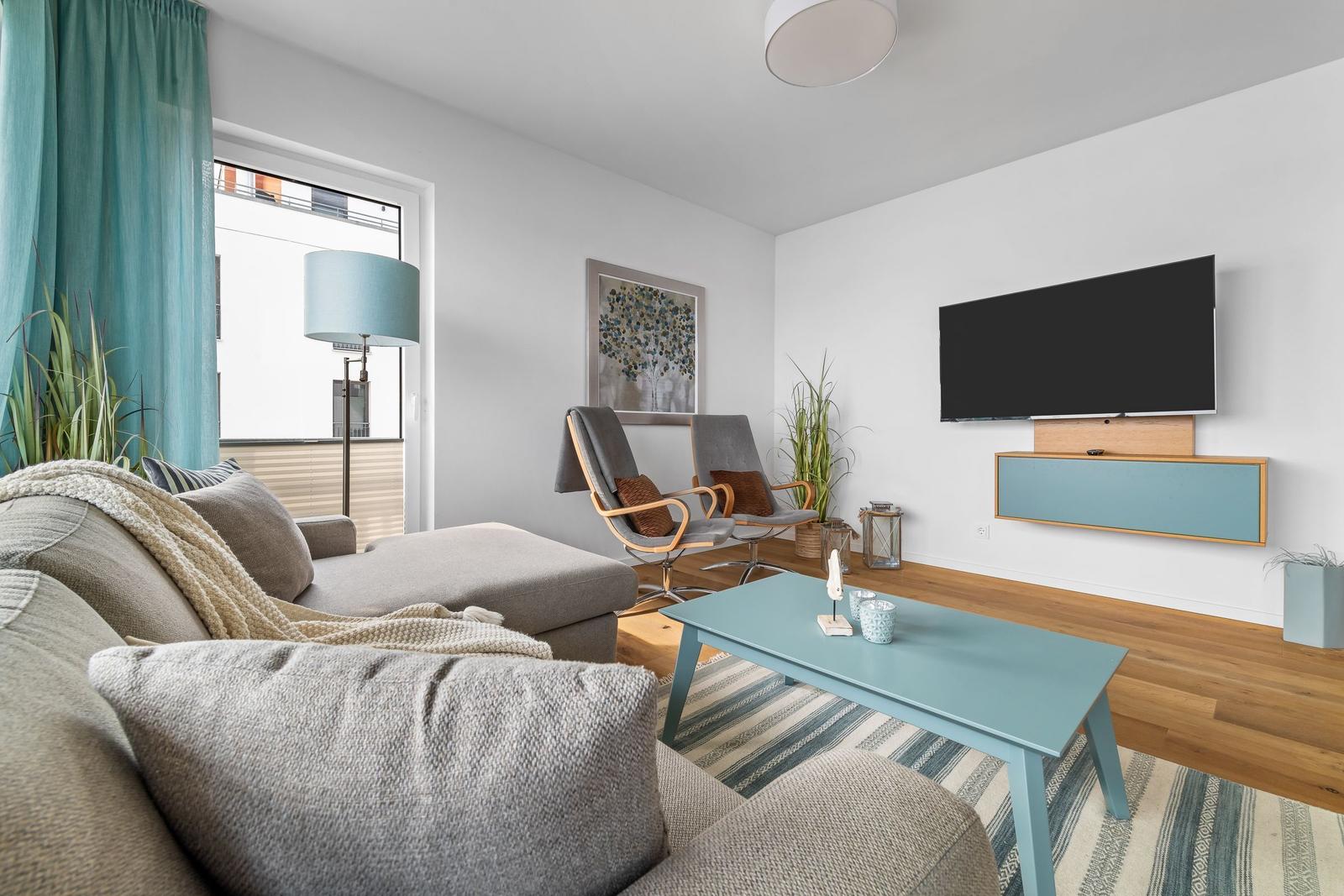 Wohnzimmer mit Sofa, Fernseher und Holzboden.
