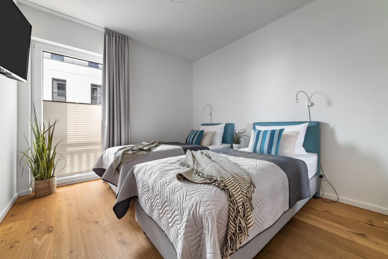 Zwei Betten mit Kopfteil, Fenster, TV und Pflanze
