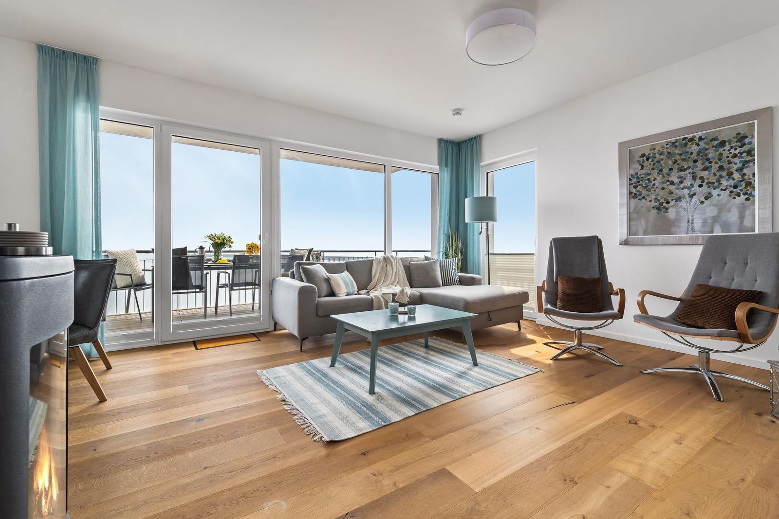 Wohnzimmer mit Sofa, zwei Sessel und Terrasse mit Meerblick.