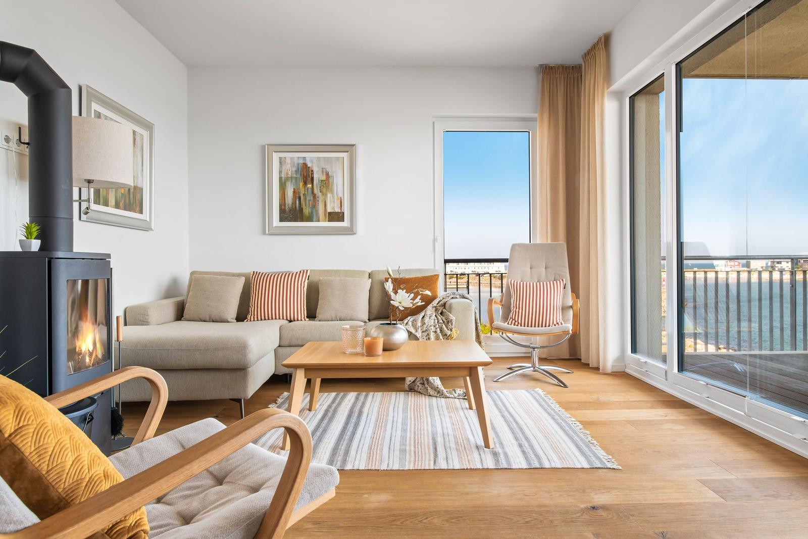 Wohnzimmer mit Sofa, Kamin und Blick aufs Wasser