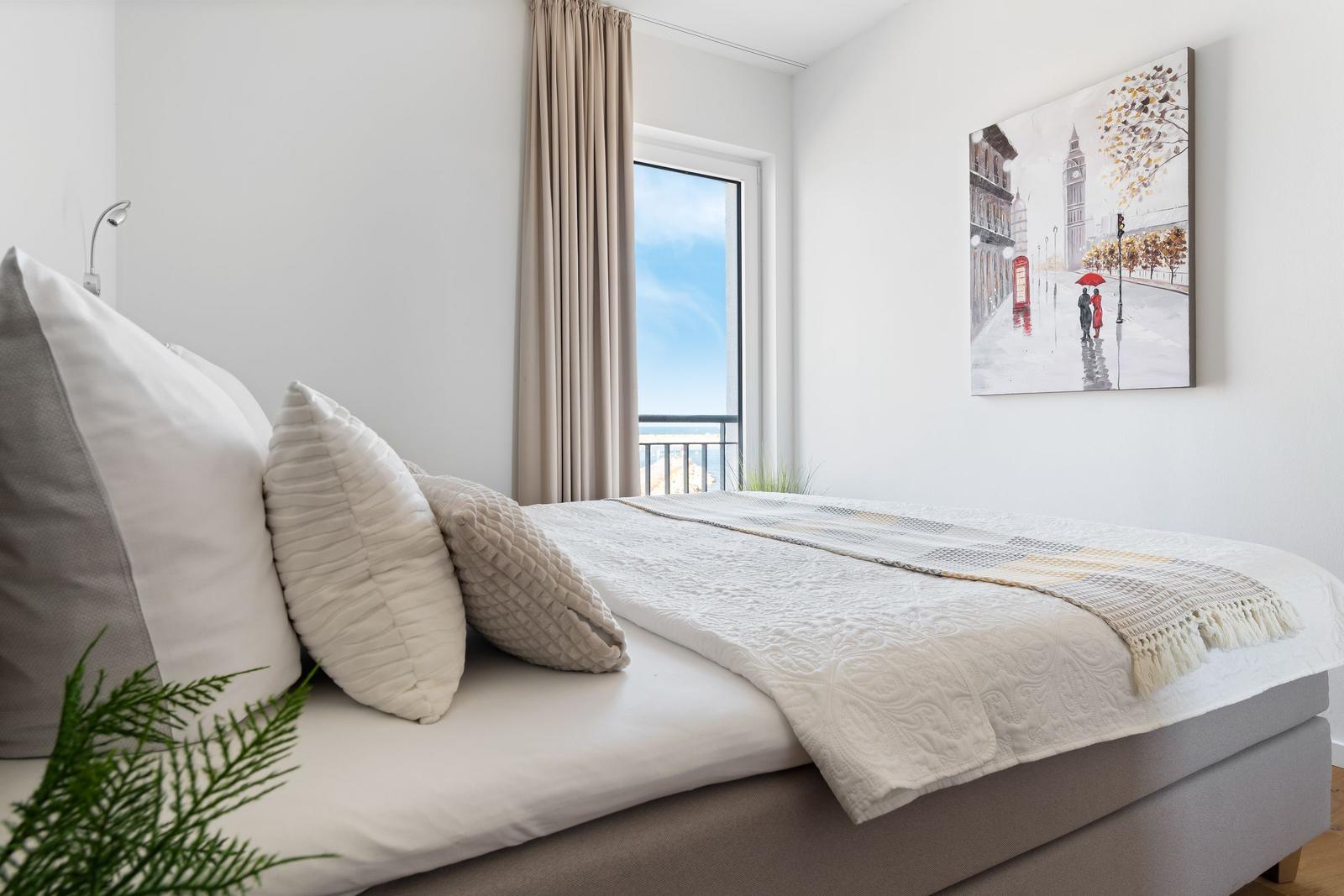 Schlafzimmer mit Bett, Fenster und Wandbild.