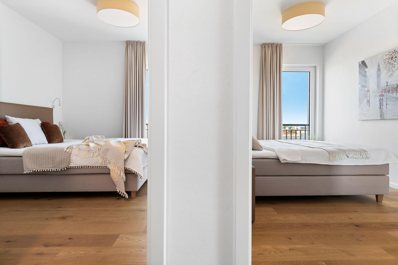 Schlafzimmer mit Bett, Vorhängen und Fensterblick auf Balkon
