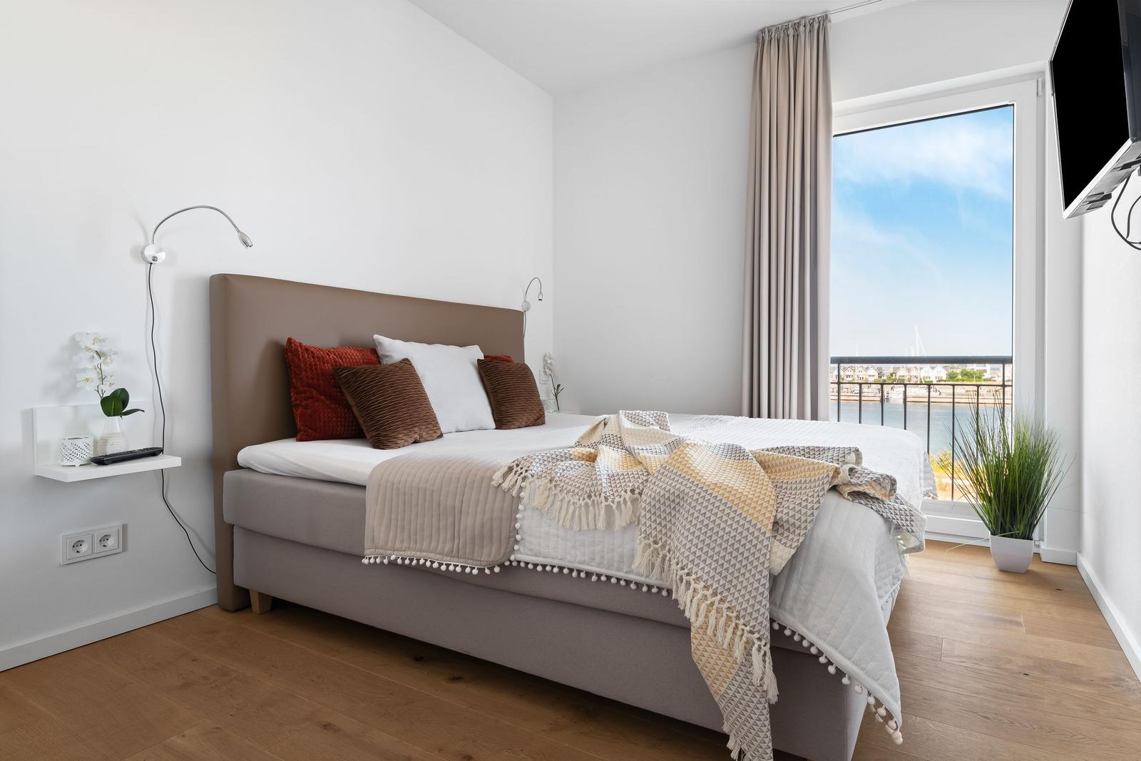 Schlafzimmer mit Bett, Fensterblick auf Hafen und TV.