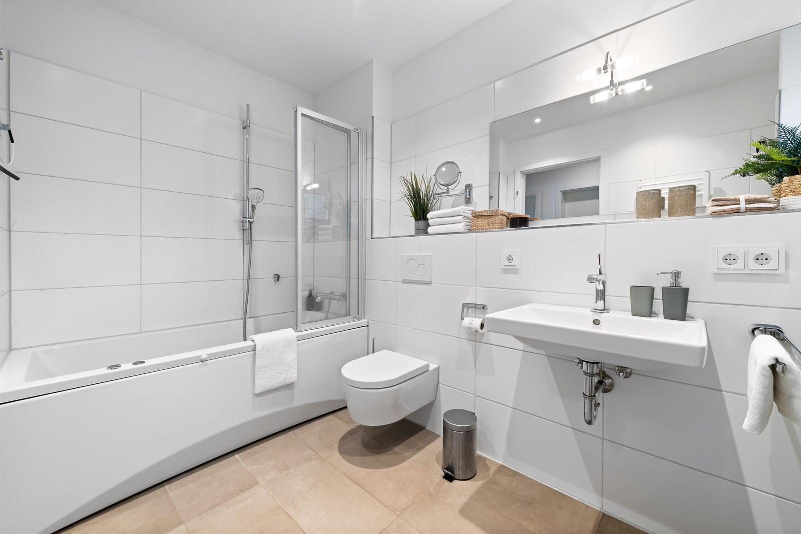 Badezimmer mit Badewanne, Dusche, Waschbecken und Spiegel