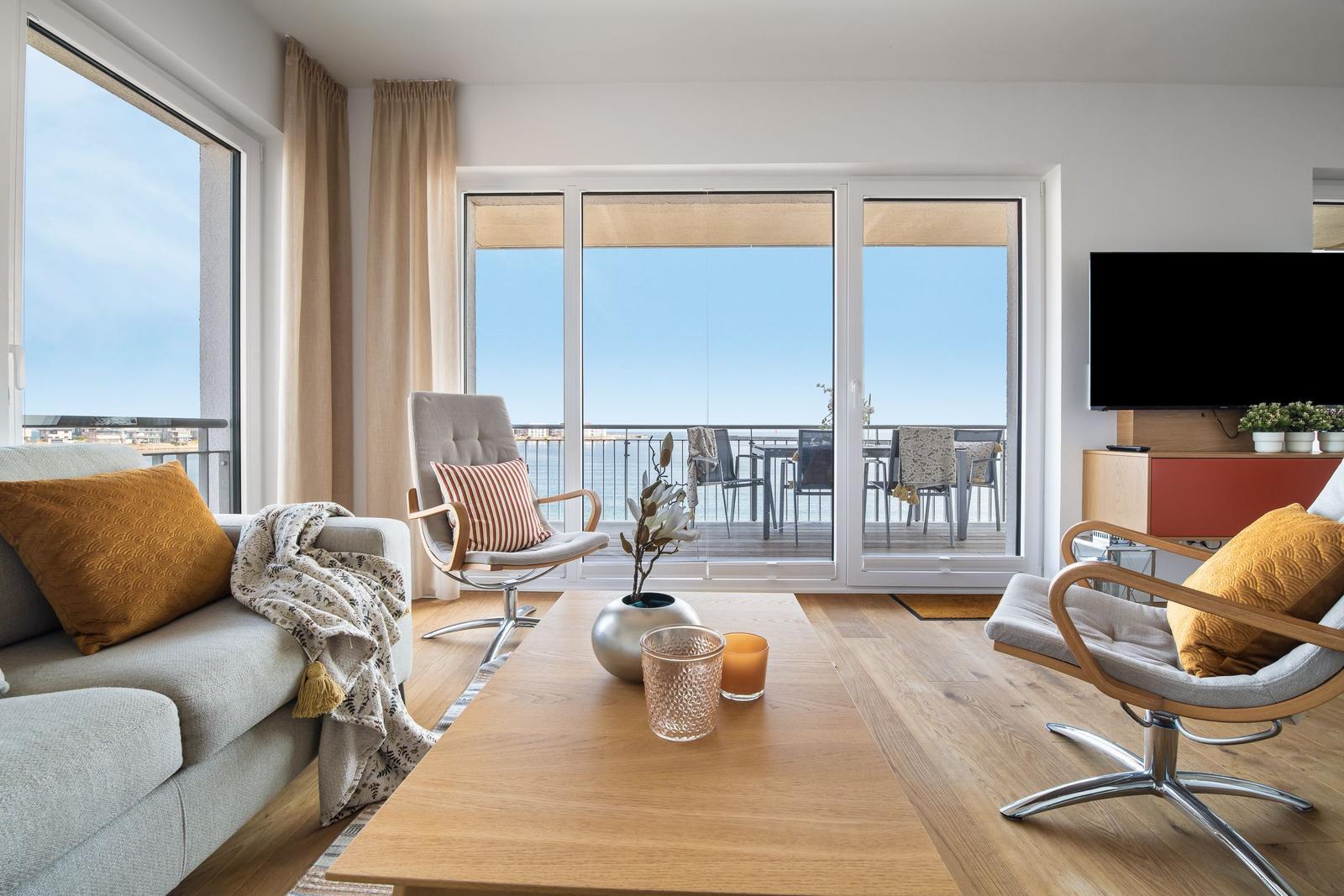 Wohnzimmer mit Blick auf den Balkon und Meer. Möbel und Dekoration sind modern.