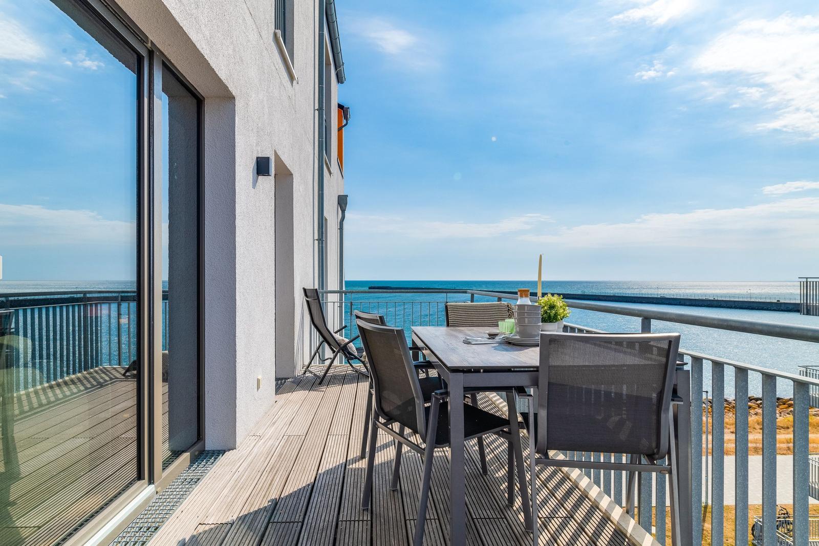 Terrasse mit Tisch und Stühlen bietet Meerblick. Holzdecke und Metallgeländer.