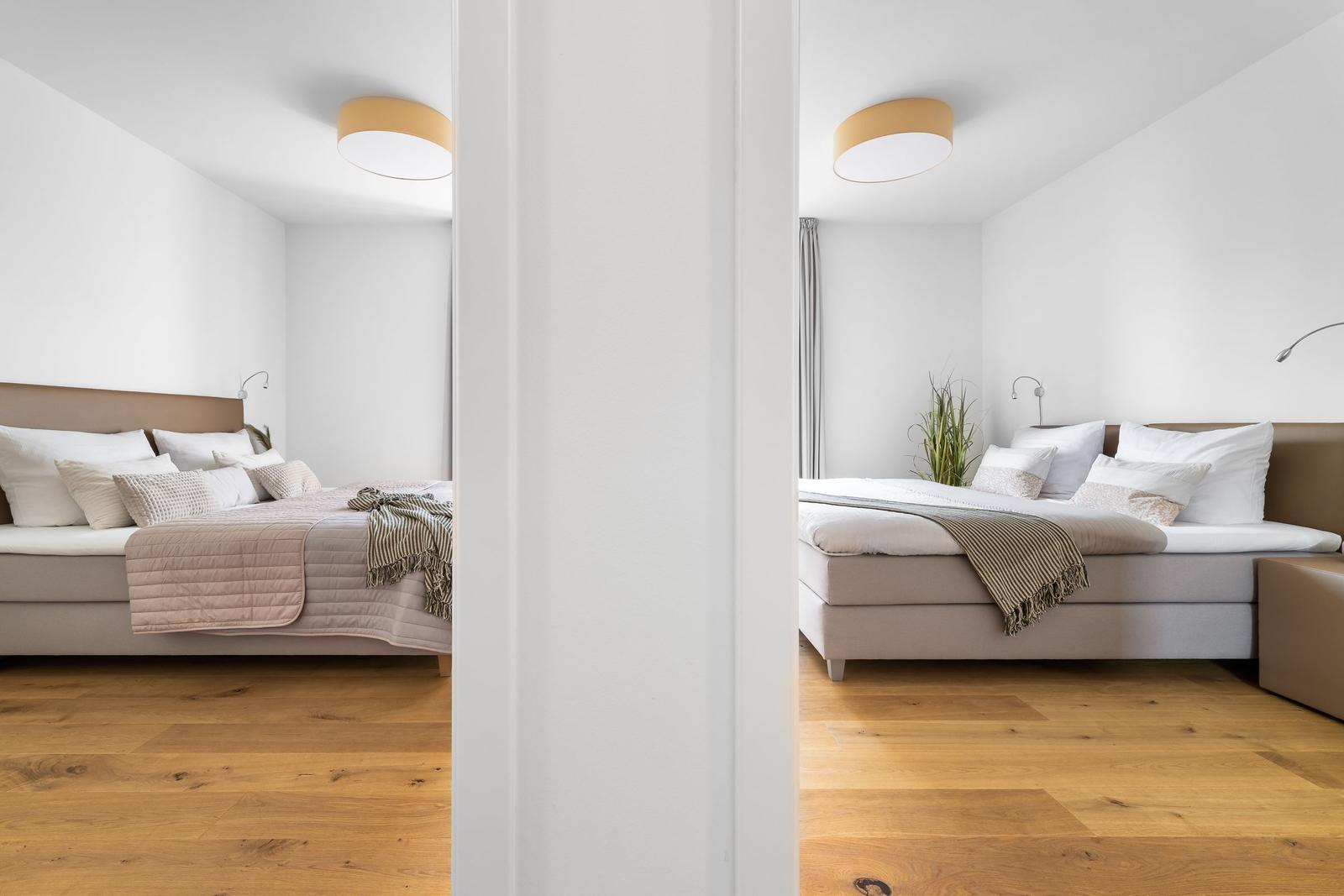 Zimmer mit Bett, Holzboden und Deckenleuchte