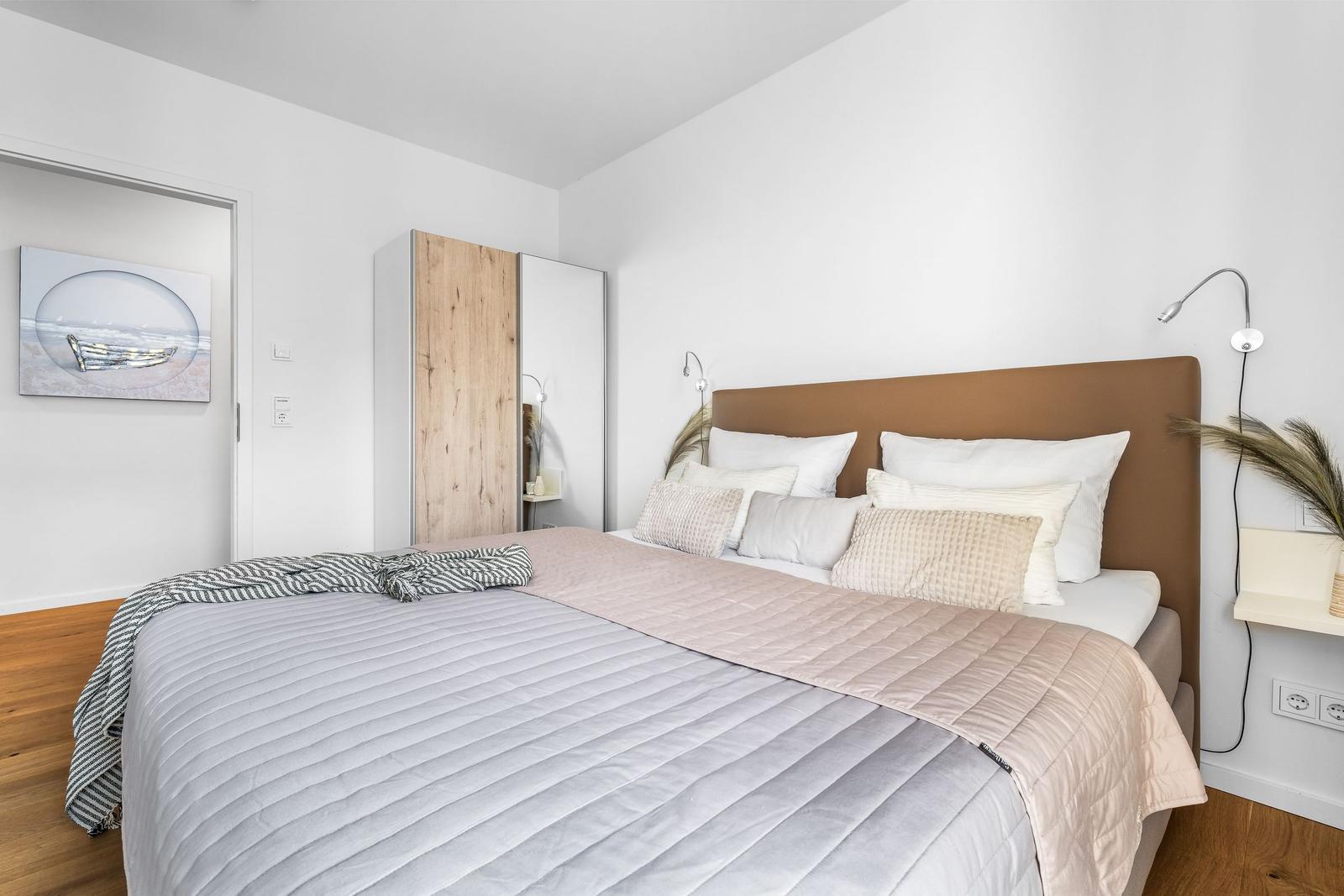 Schlafzimmer mit Bett, Nachttisch und Wandbild.