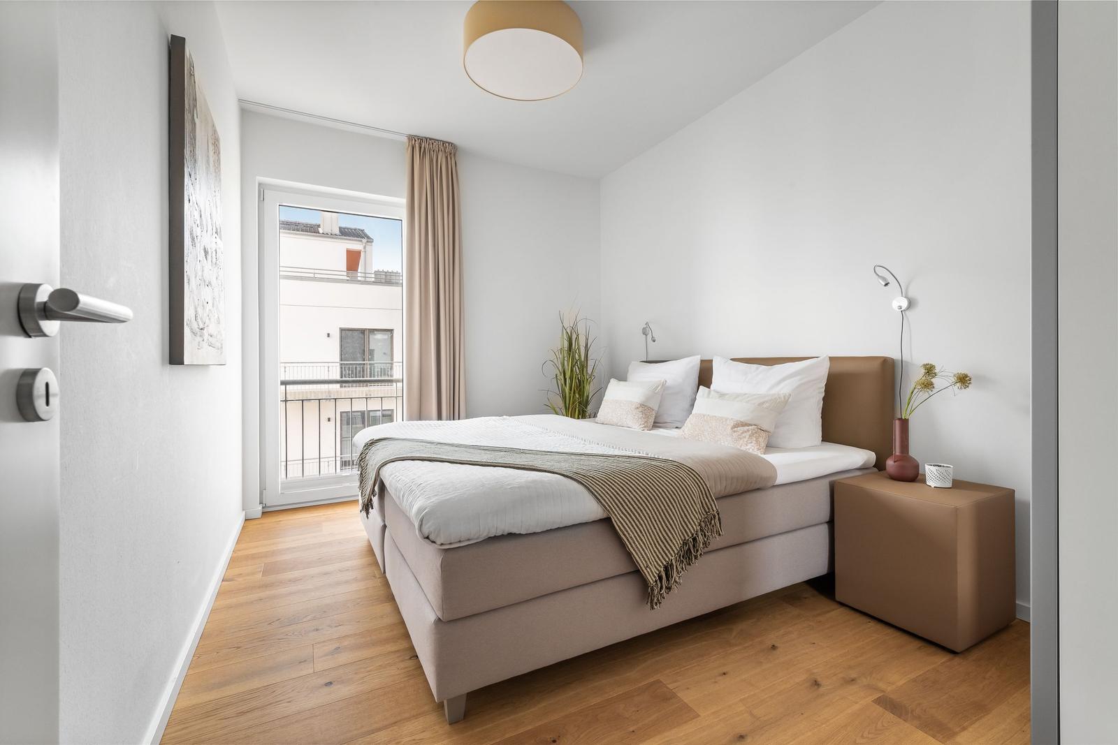Schlafzimmer mit Bett, Nachttisch und Fenster zur Aussicht.