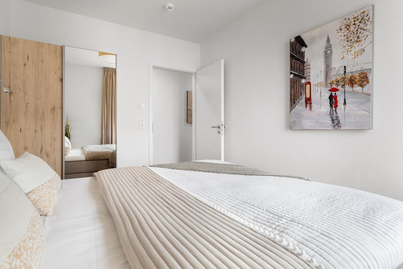 Schlafzimmer mit Bett, Wandbild und Spiegel