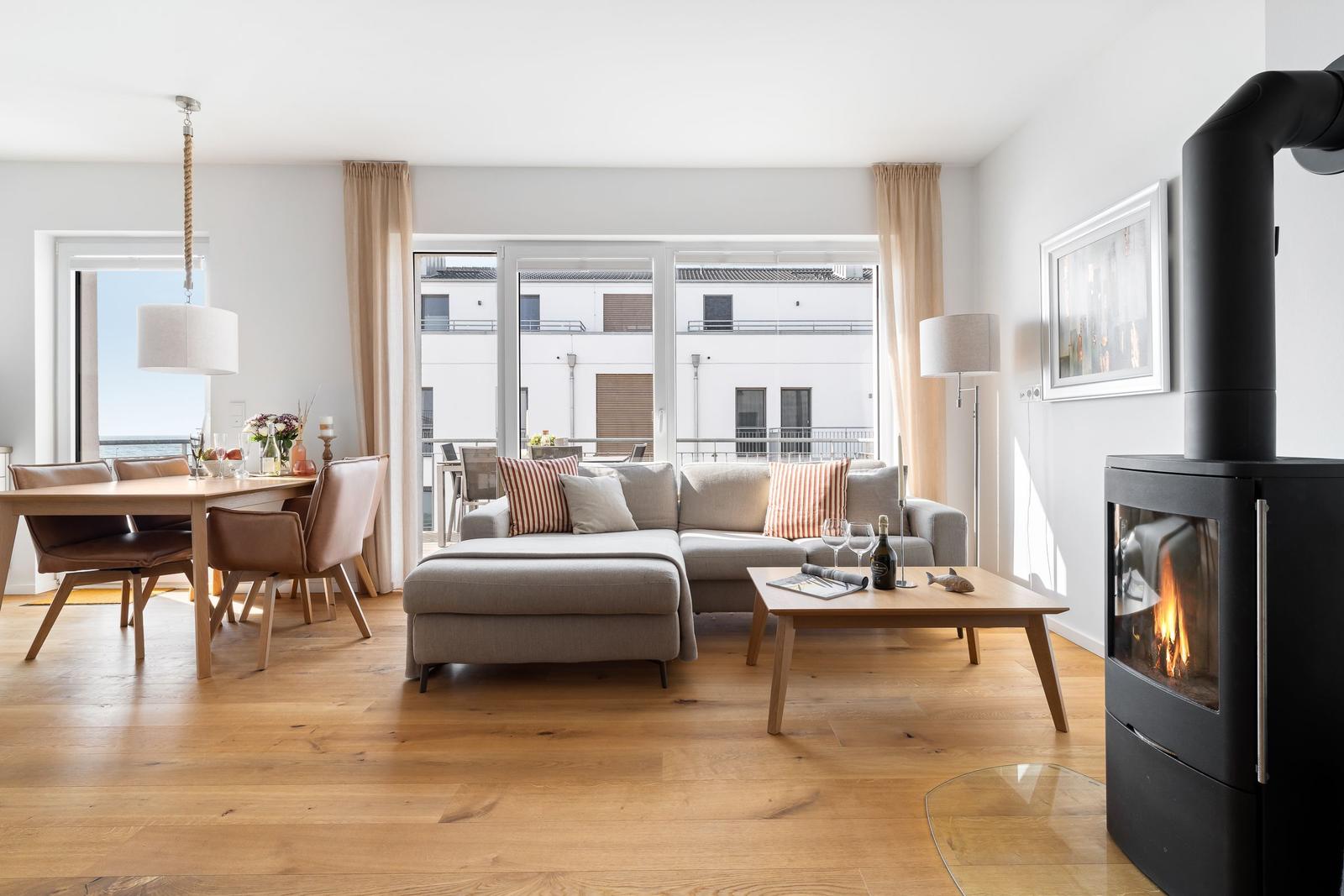 Wohn- und Essbereich mit Kamin, Sofa und Blick auf Balkon.