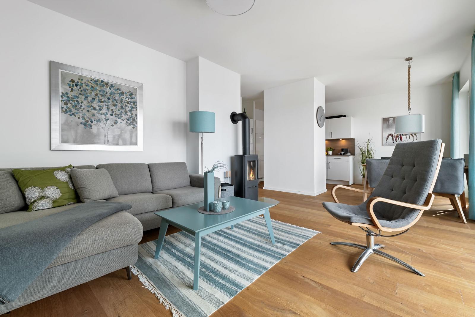 Wohnzimmer mit Sofa, Kamin und Sessel auf Holzboden.