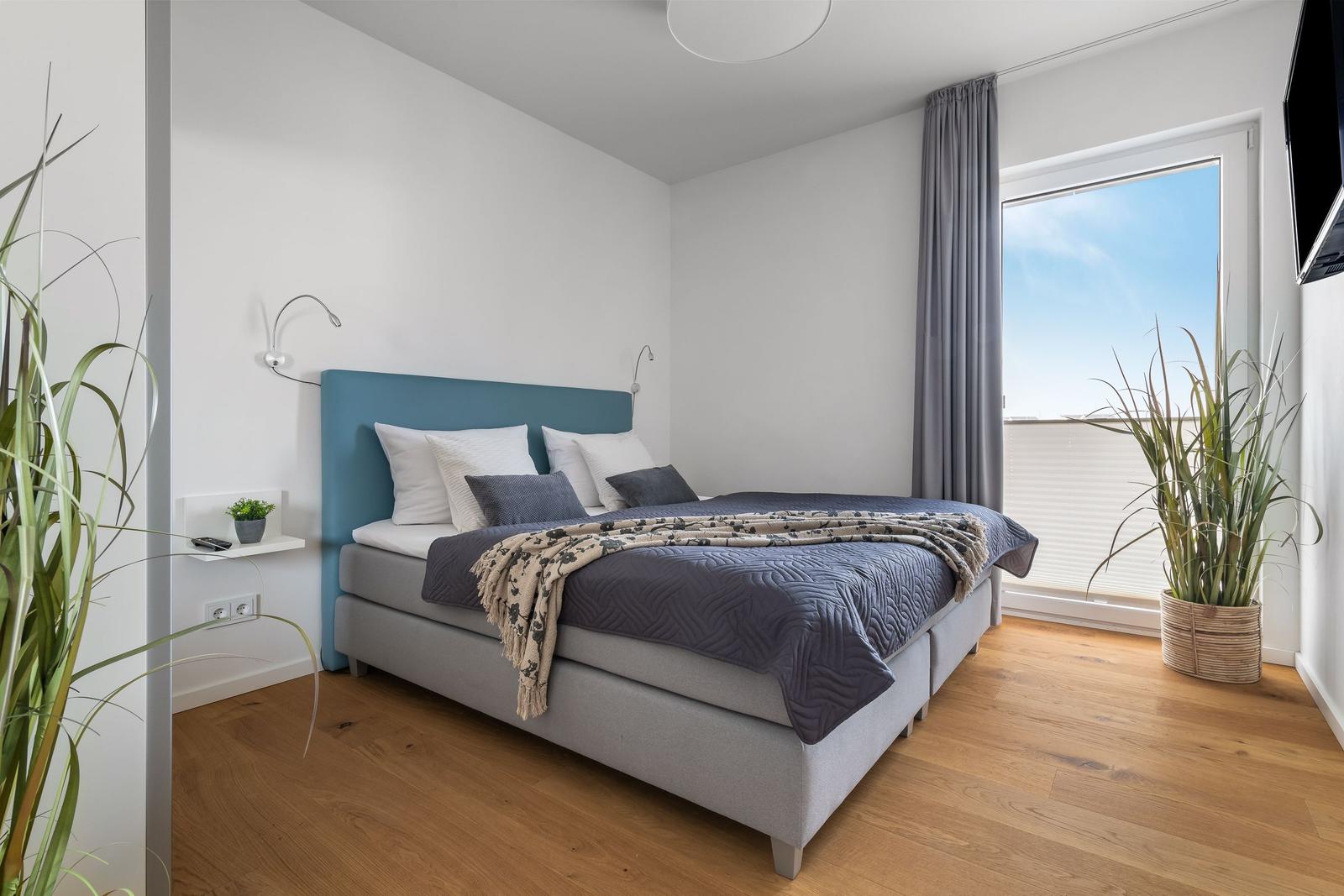 Schlafzimmer mit Bett, Fenster und Pflanzen