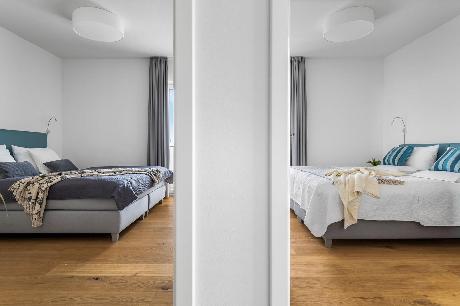Zwei Schlafzimmer mit Betten, Holzboden und Fenstern mit Vorhängen.