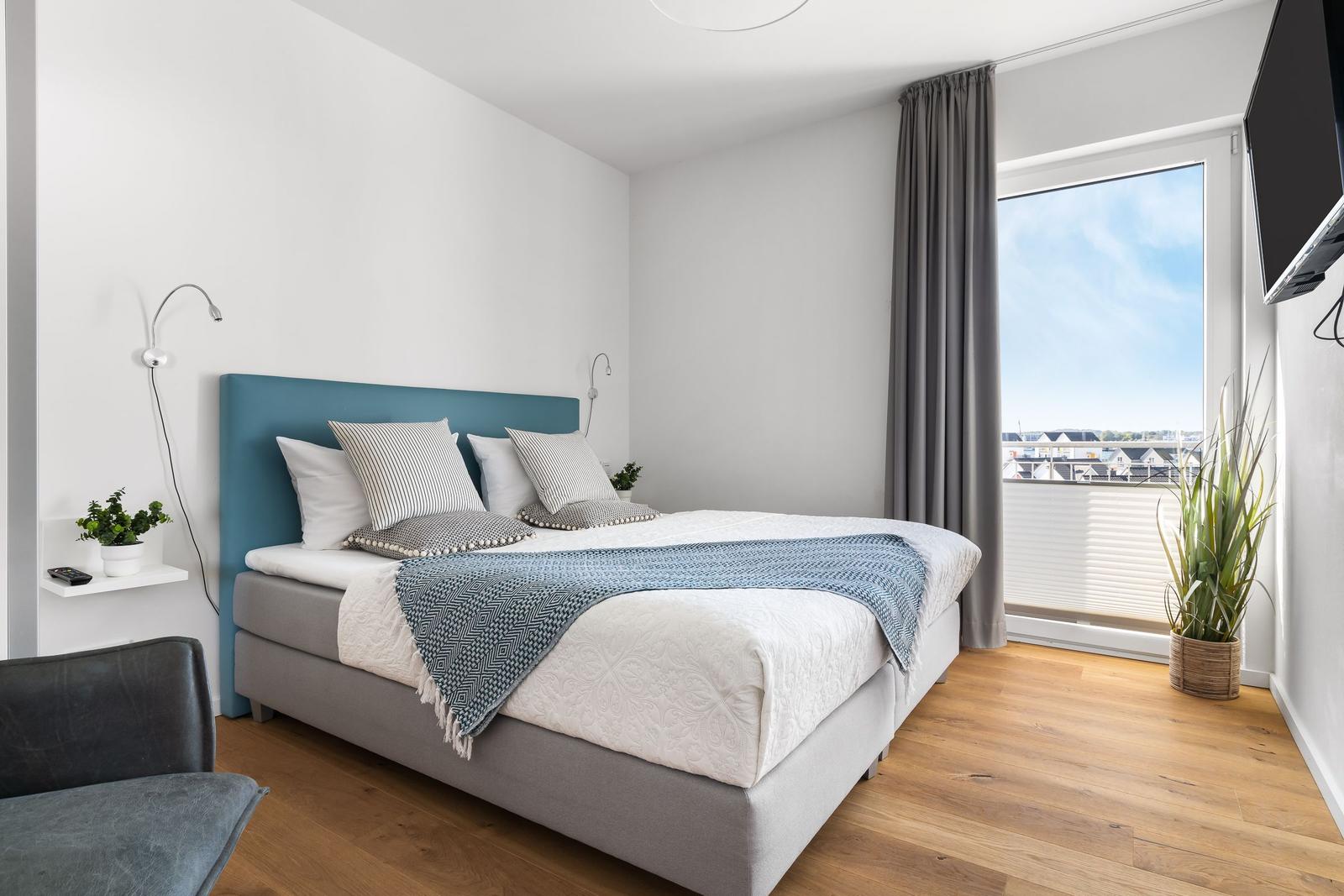 Bedroom with double bed, window, and plants.