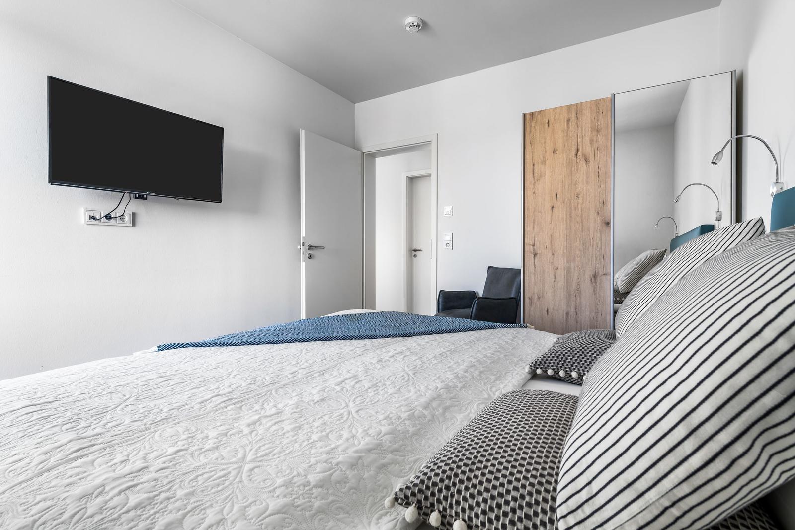 Bedroom with bed, TV, and mirror