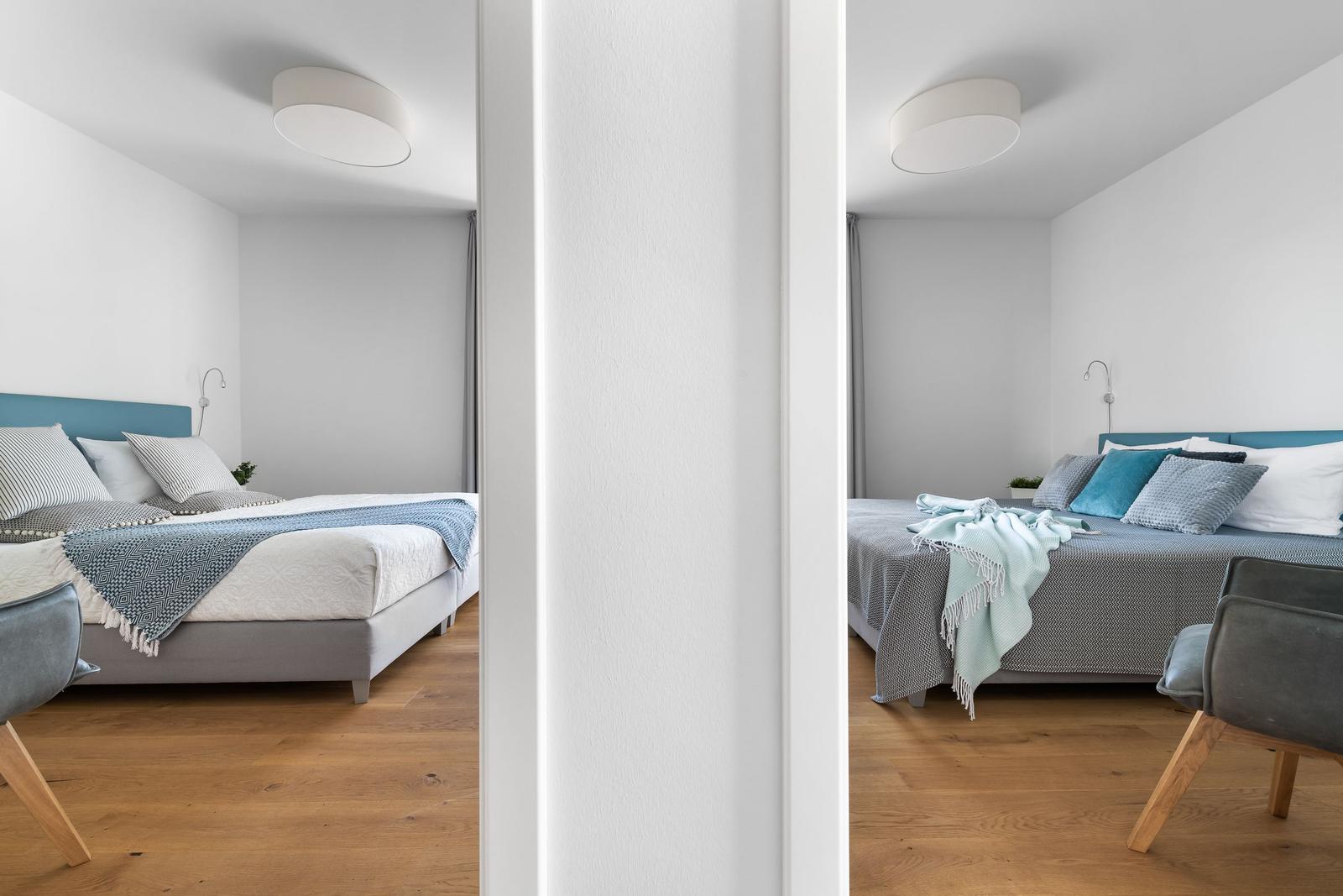 Two bedrooms with beds, blankets, and chairs. Wooden floor and white walls.