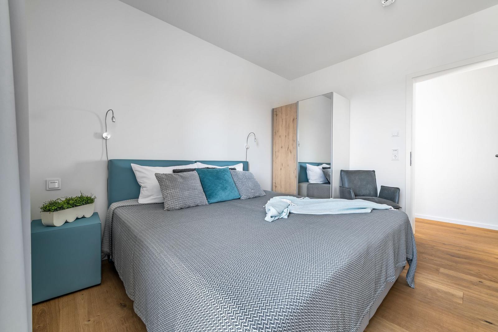 Bedroom with double bed, nightstand, mirrored wardrobe, and seating.
