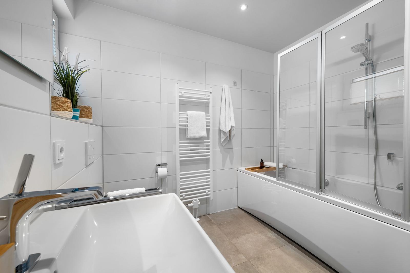 Bathroom with bathtub, shower, and towel rack.