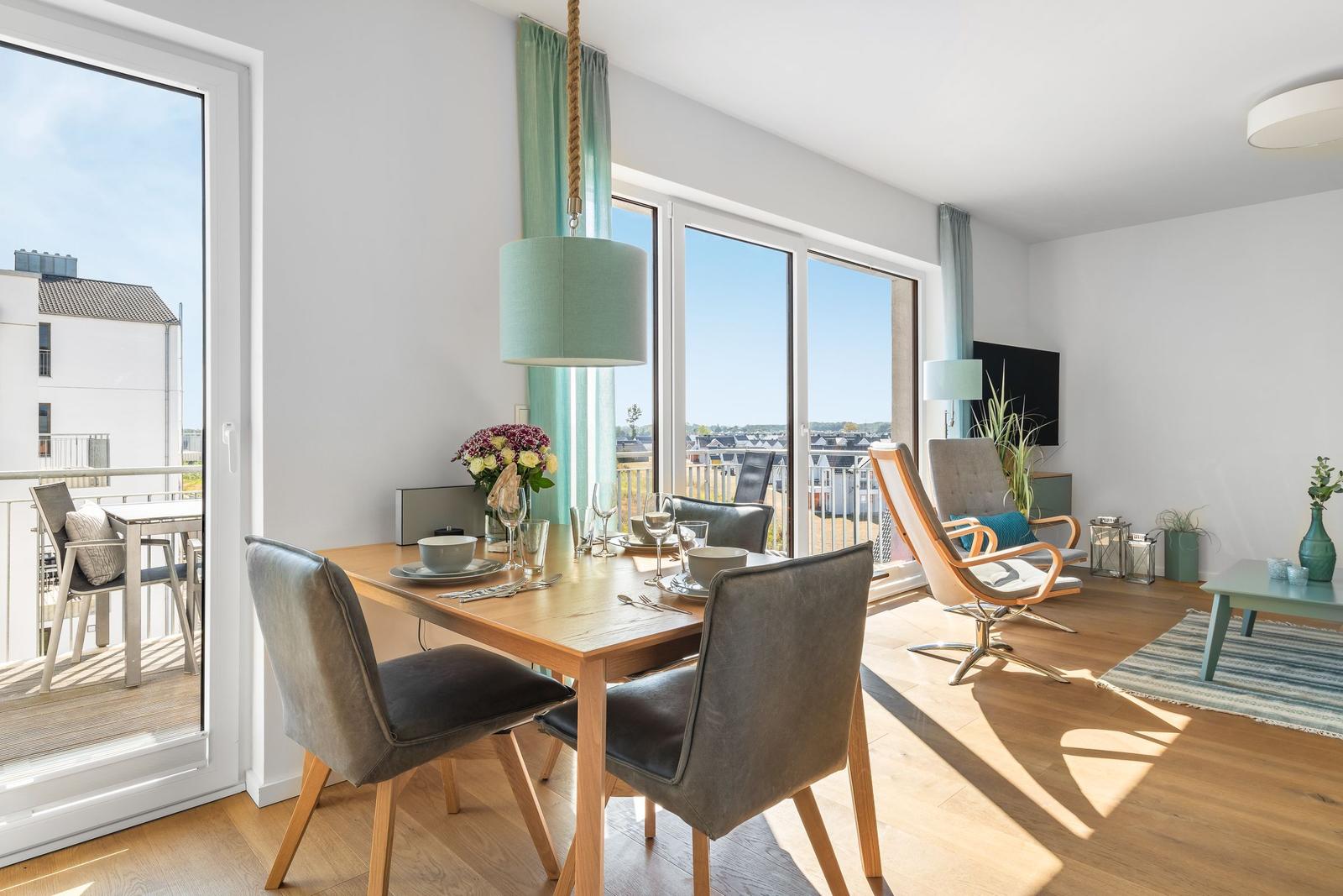 Dining area with table and chairs, view to balcony and living room with seating.