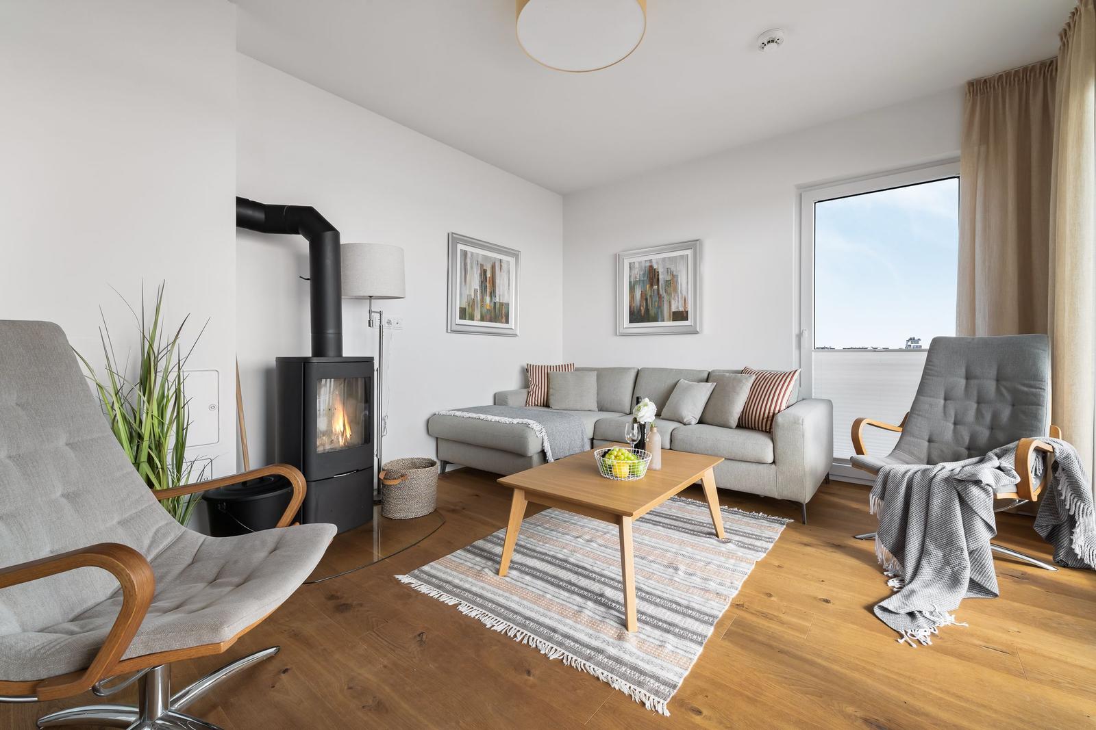 Wohnzimmer mit Sofa, Kamin und zwei Sesseln auf Holzboden.