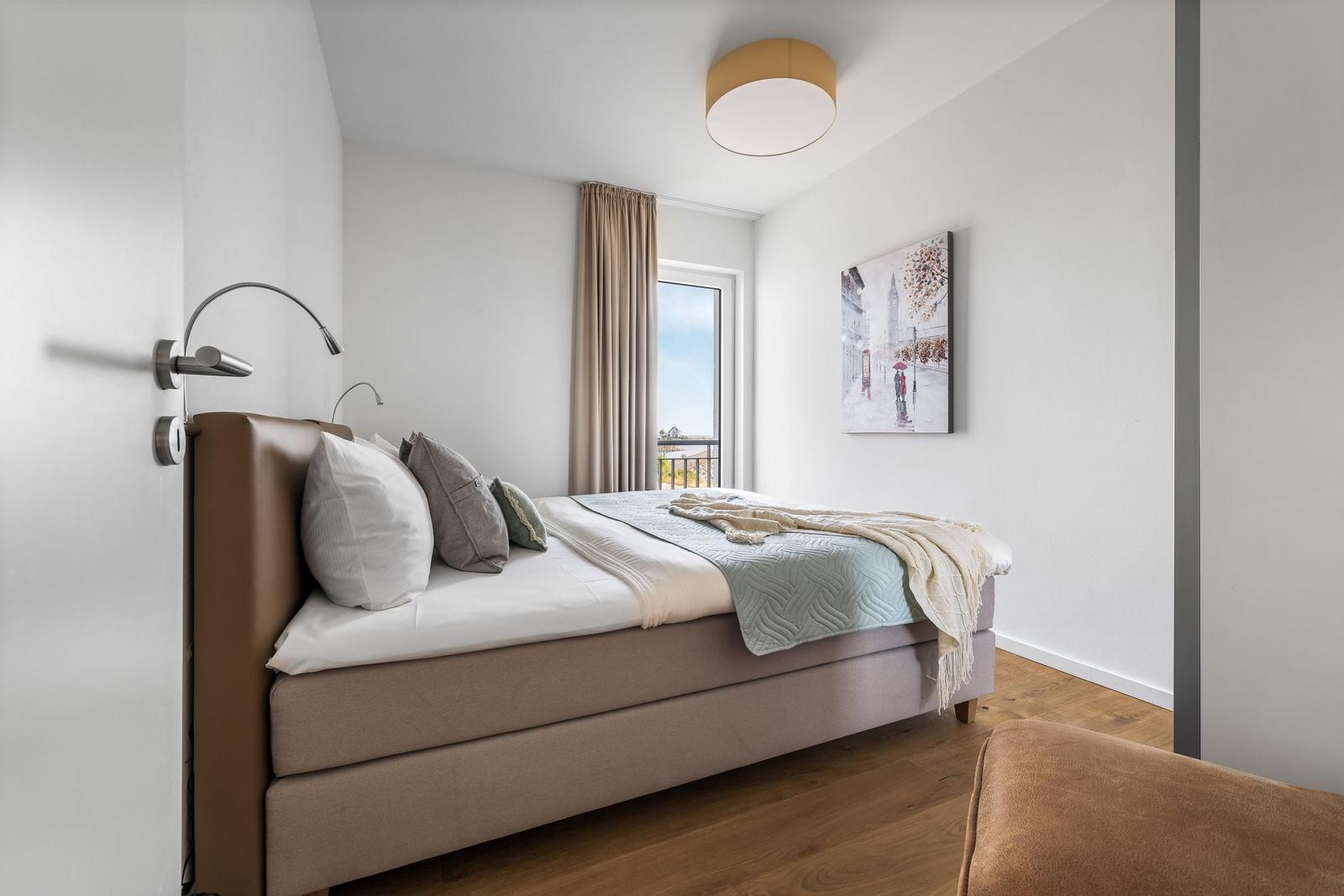 Schlafzimmer mit Bett, Fenster und Wandbild.