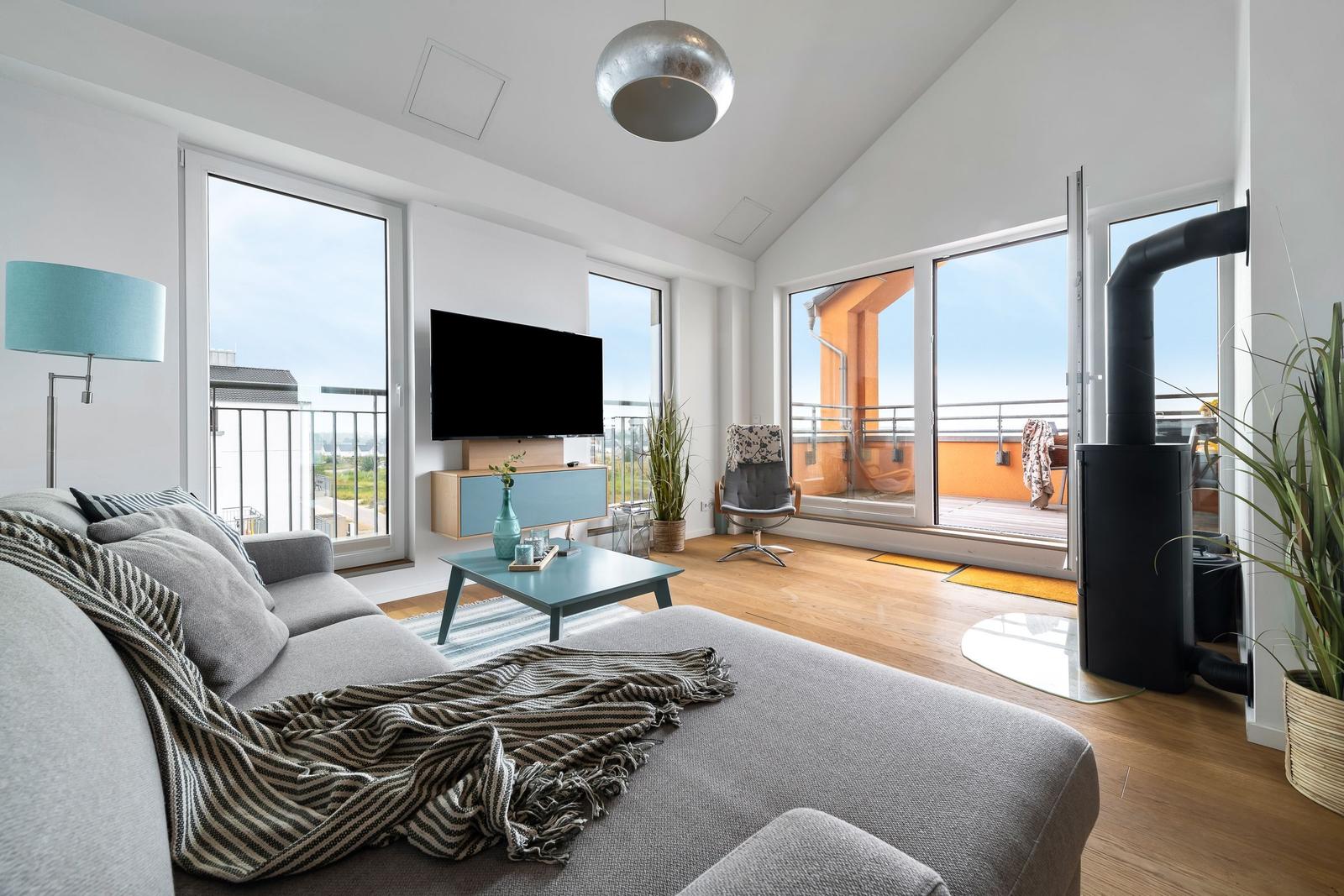 Wohnzimmer mit Sofa, Fernseher und Balkonansicht.