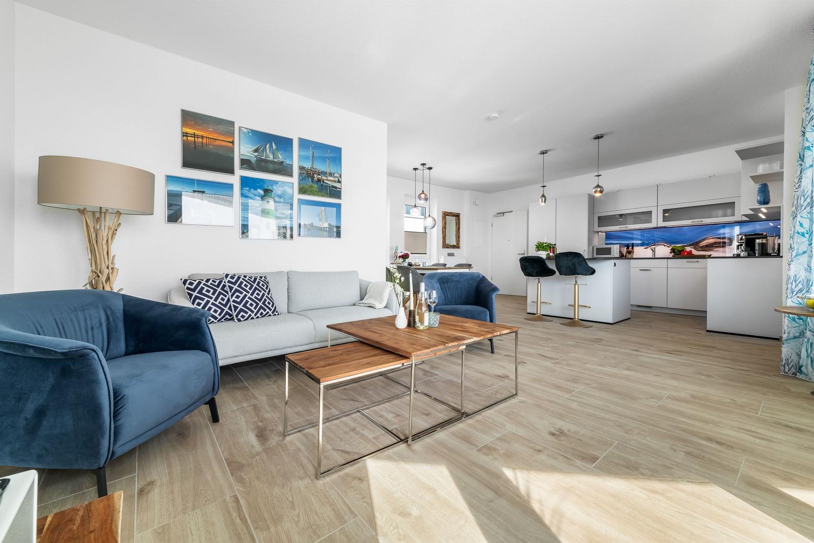 Wohnbereich mit Sofa, Sessel und Küchenbereich mit Arbeitsplatte