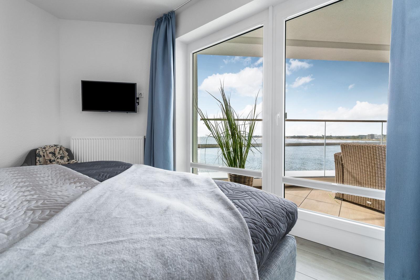 Schlafzimmer mit Blick auf die Terrasse und das Wasser.