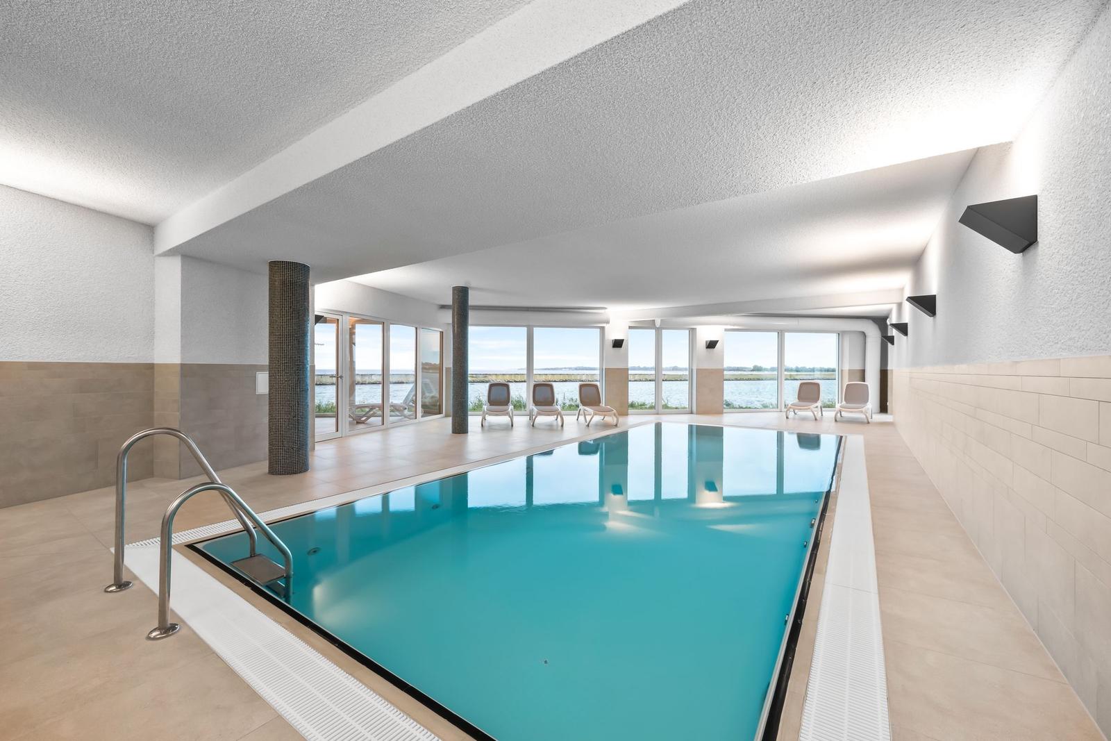 Indirekt beleuchteter Innenpool mit Blick auf Wasser und Liegestühle