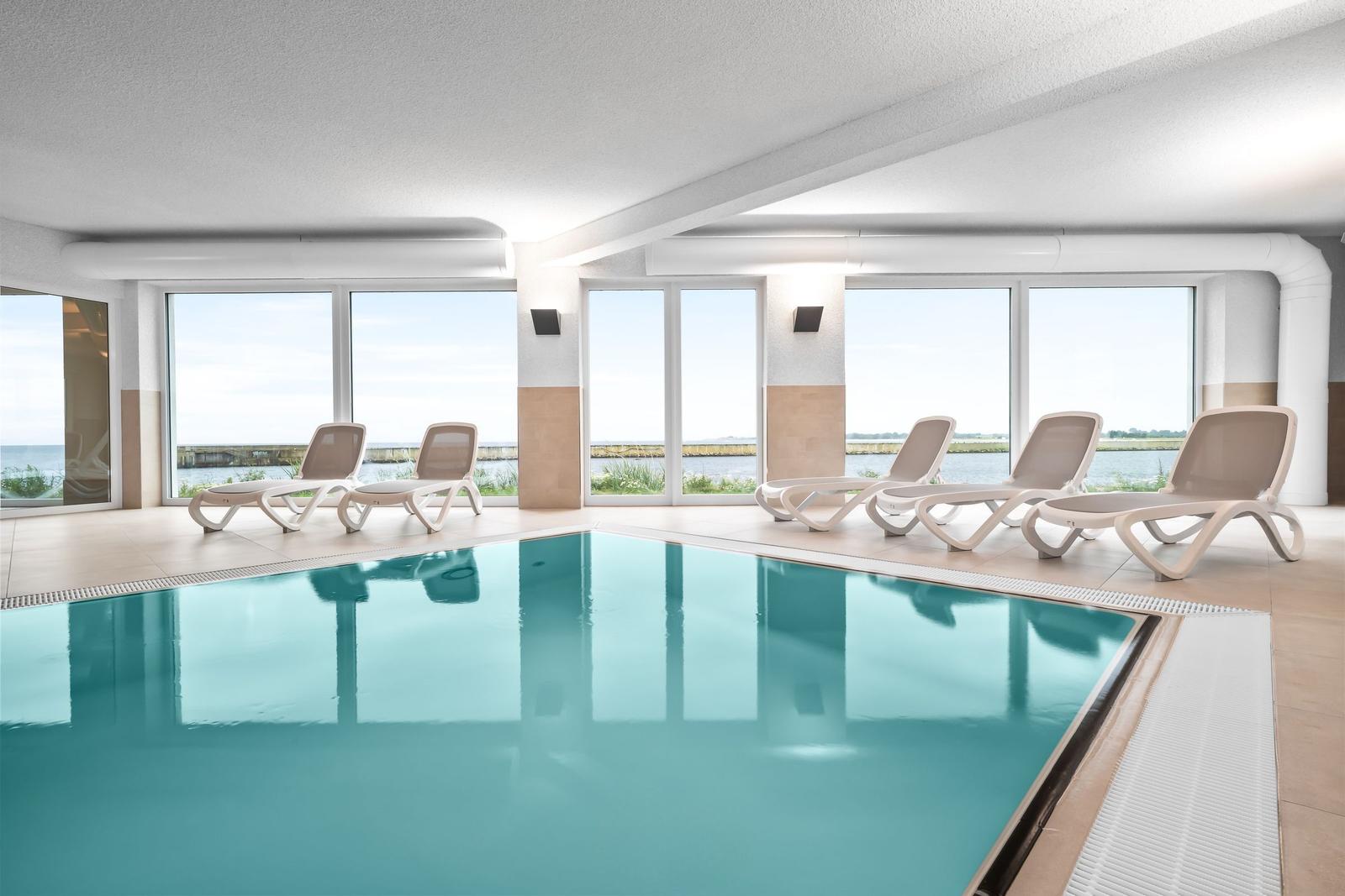 Innenpool mit Liegestühlen und Blick auf Wasser