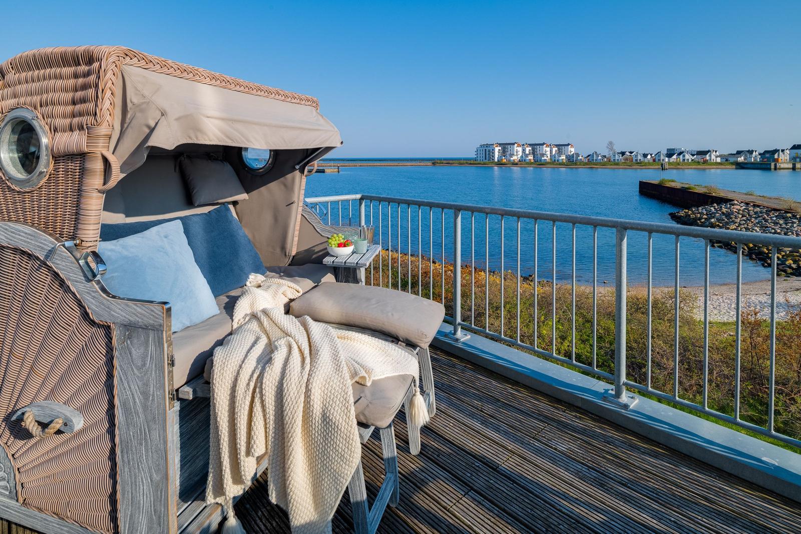 Terrasse mit Liege und Blick auf Wasser und Ferienhäuser.