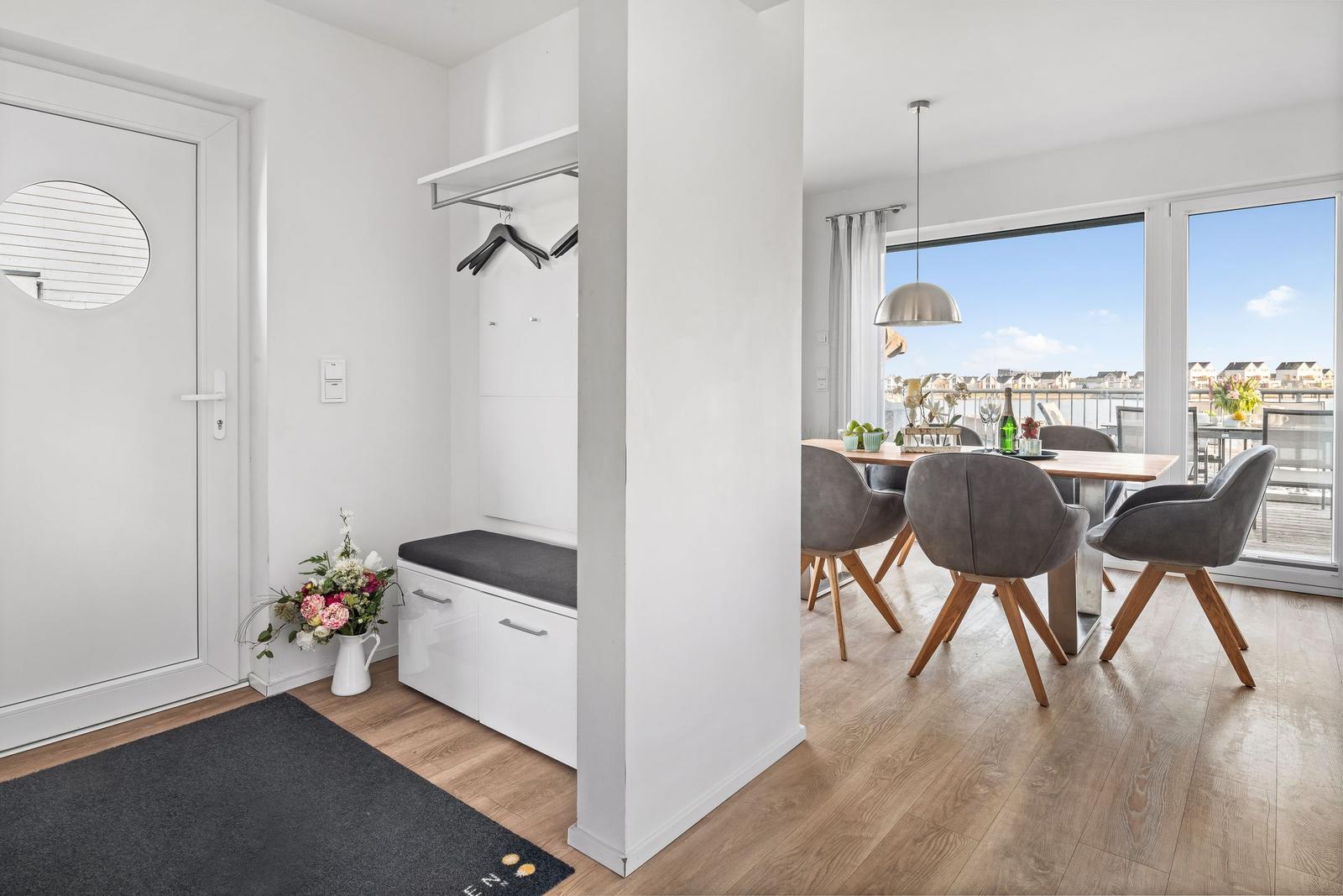Eingangsbereich mit Garderobe und Essbereich mit Tisch und Stühlen.