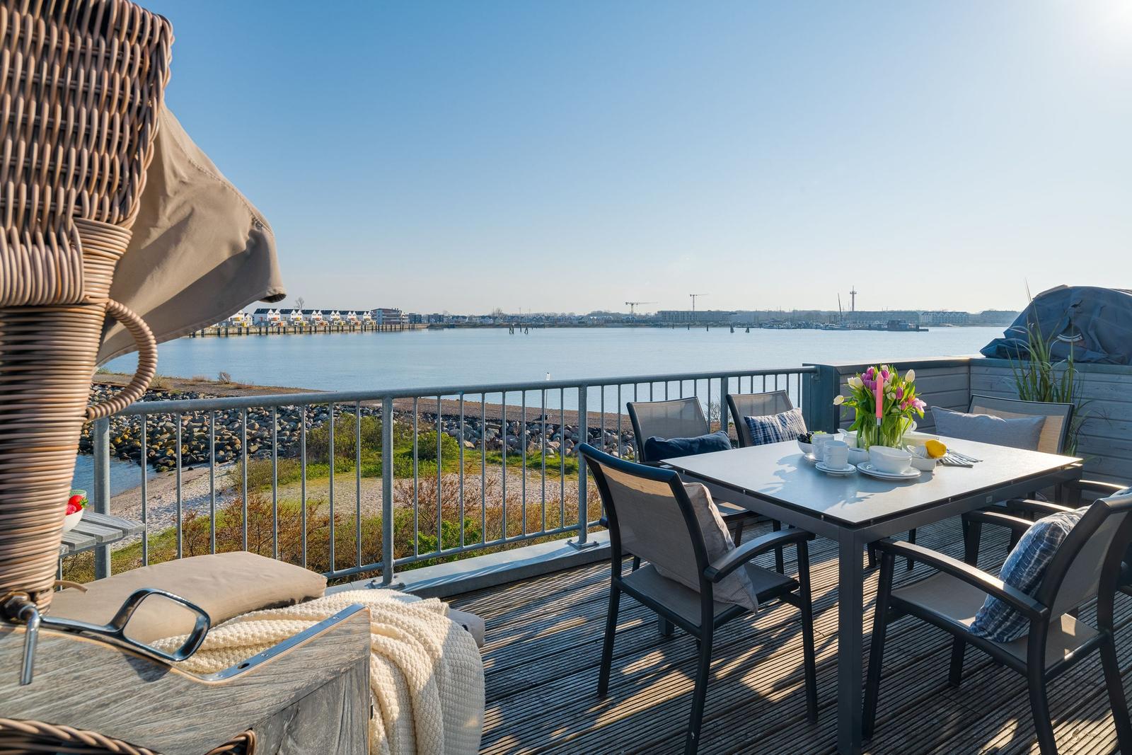 Terrasse mit Tisch, Stühlen und Meerblick. Grill und Sonnenschirm sind vorhanden.