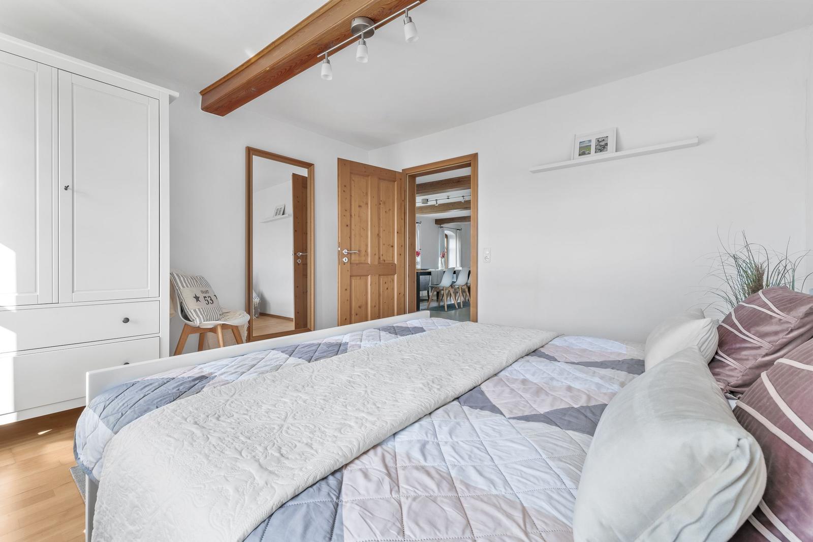 Schlafzimmer mit Bett, Kleiderschrank und Blick in angrenzende Räume.