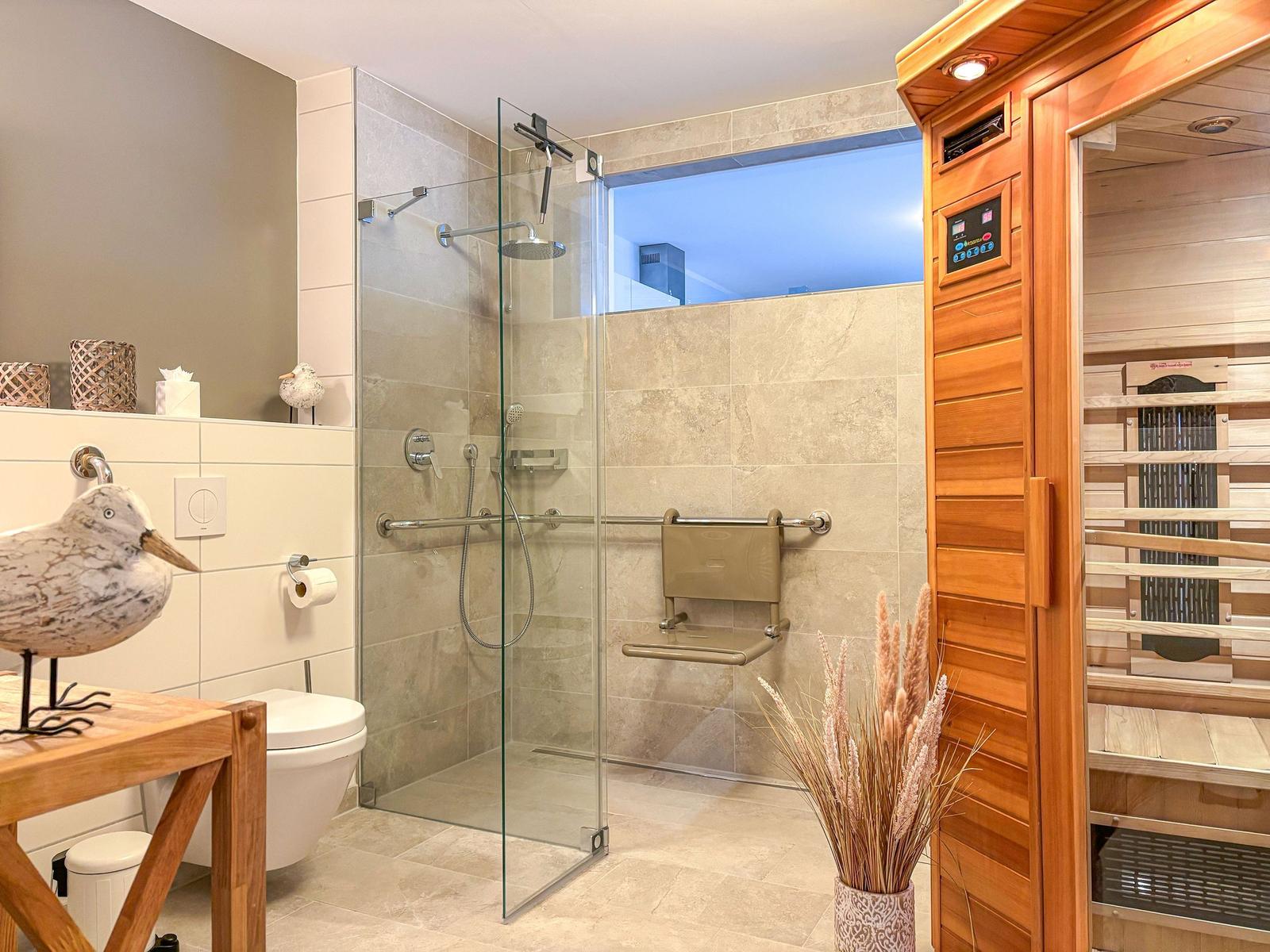 Bad mit Dusche, Toilette und Sauna. Glaswand, Holzverkleidung und Dekoration.