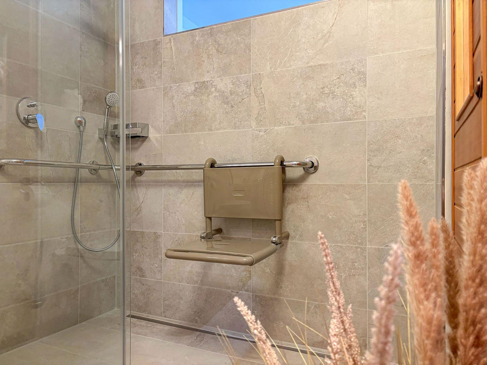 Duschbereich mit Sitzbank und Handlauf an der Wand