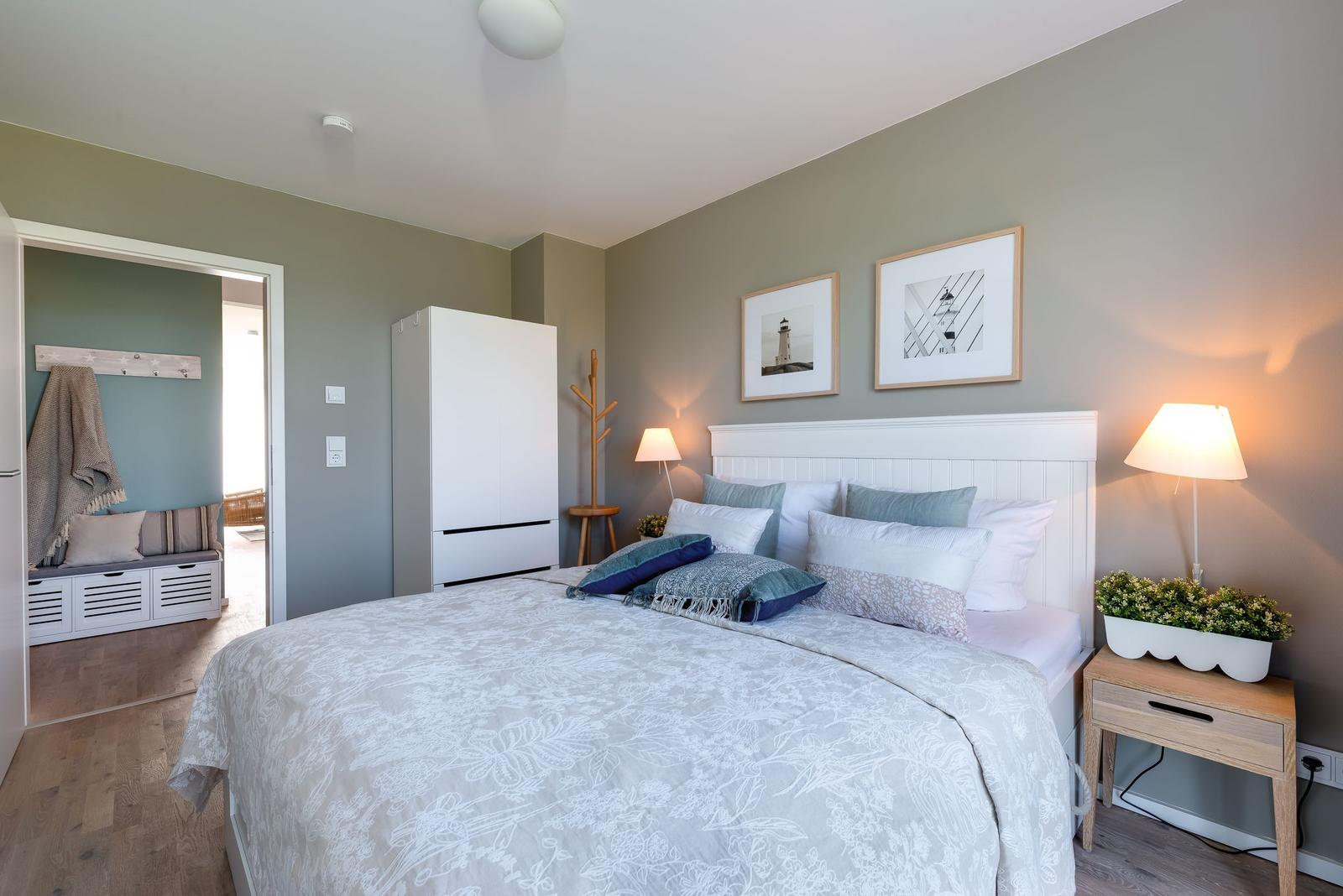 Schlafzimmer mit Bett, Nachttisch und Kleiderschrank. An der Wand hängen Bilder.