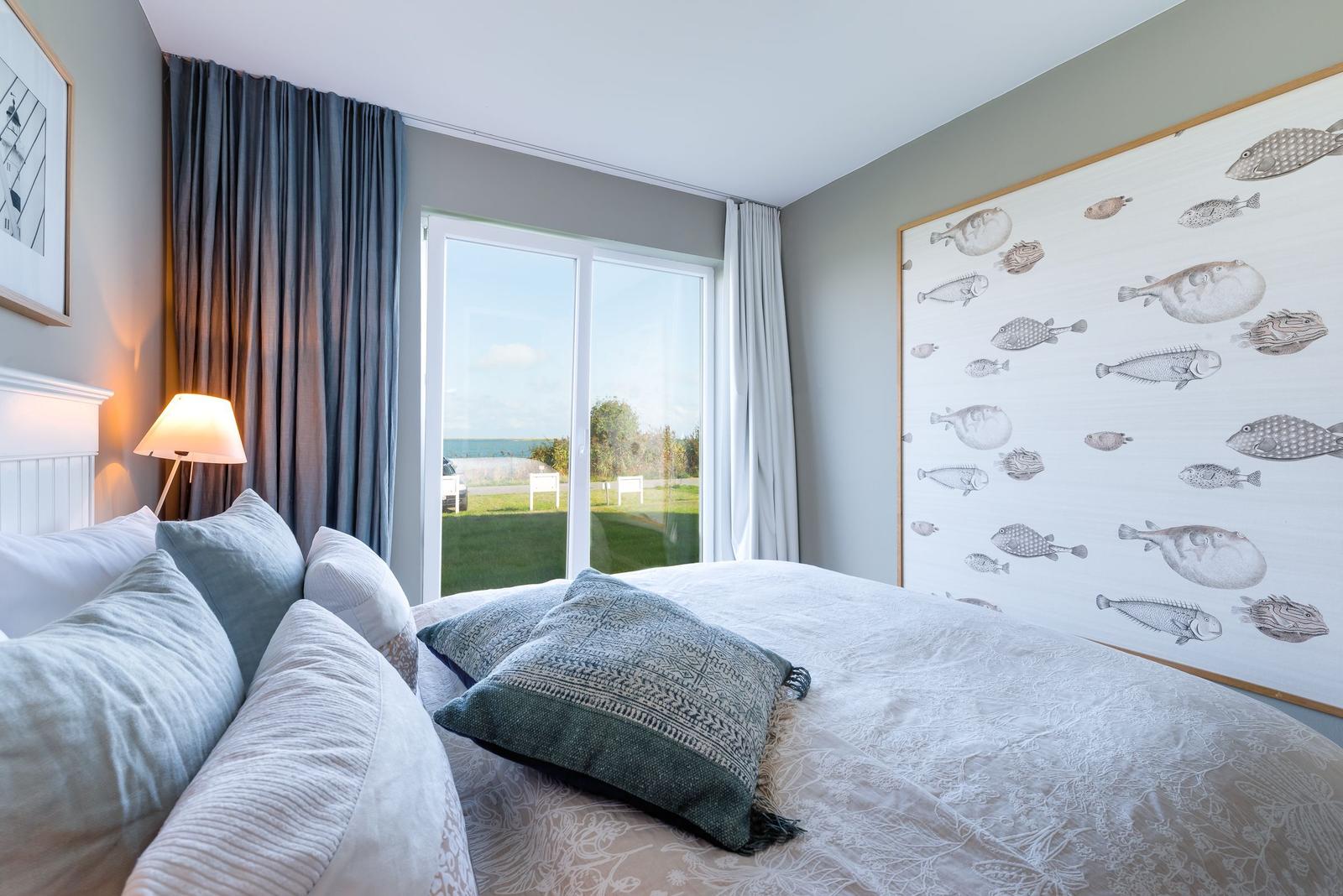 Schlafzimmer mit Bett, Fenster und Wandbild mit Fischen.