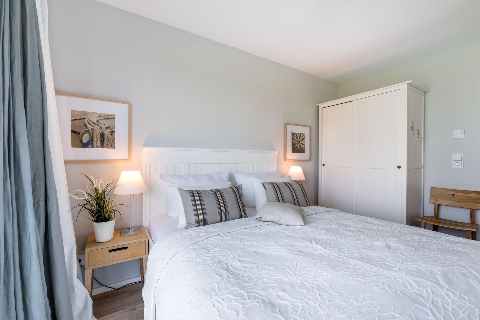 Schlafzimmer mit Bett, Nachttisch, Kleiderschrank und Stuhl.