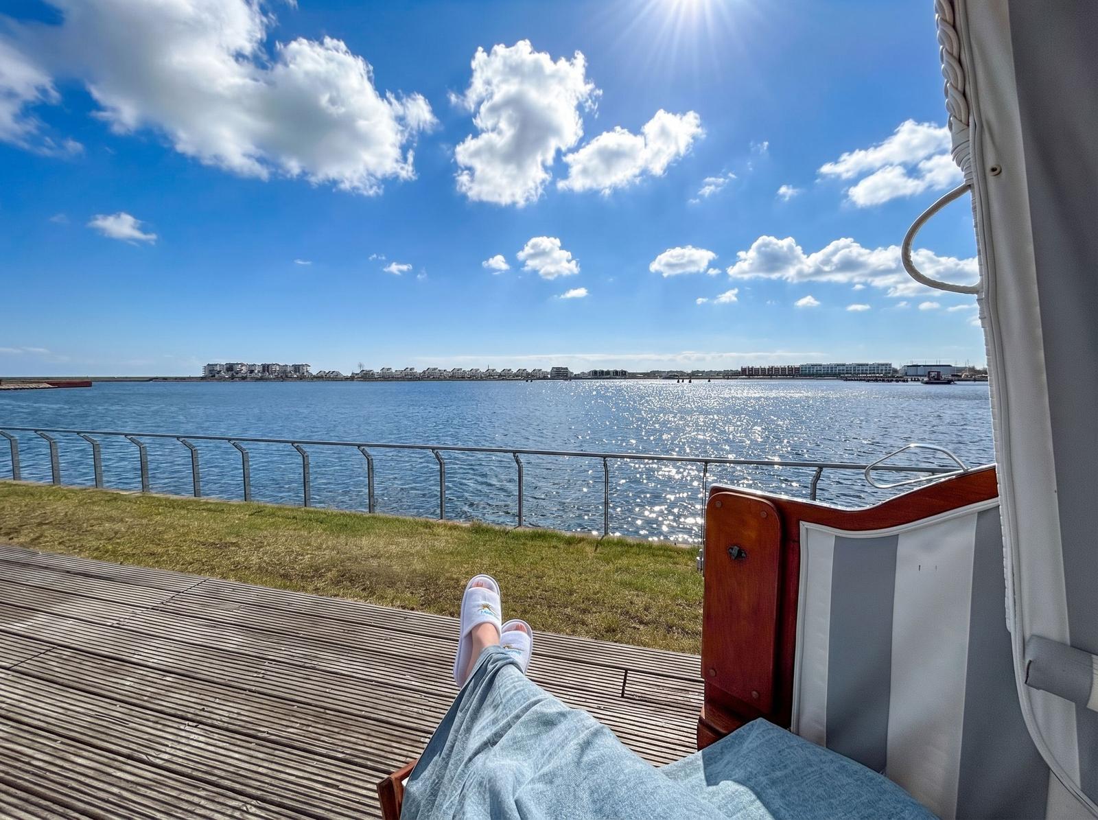 Persönliche Sicht auf einen sonnigen Tag am Wasser mit Blick auf die gegenüberliegende Uferpromenade.