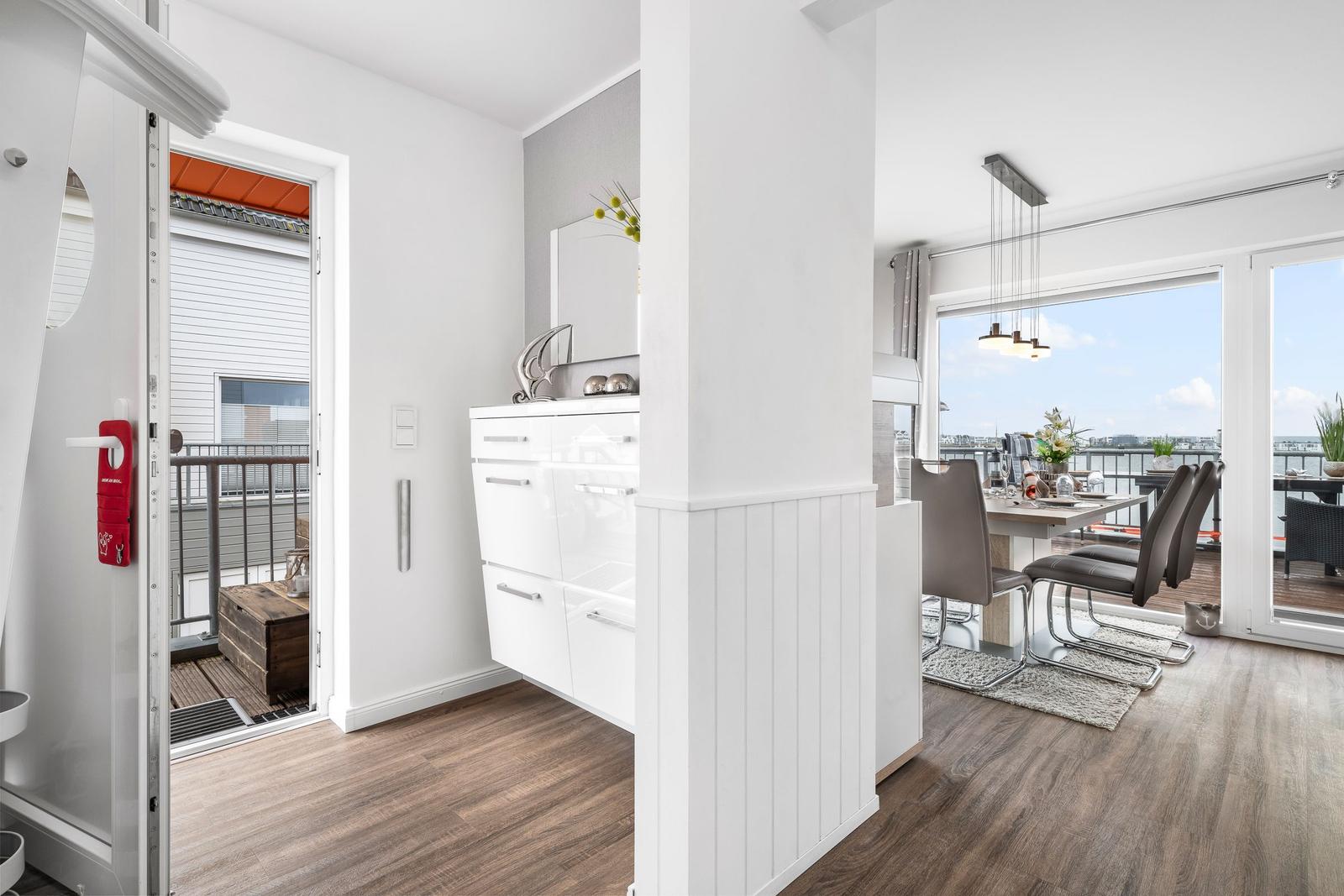 Wohnung mit Essbereich, Balkon und moderner Einrichtung. Blick auf Wasser und Himmel.