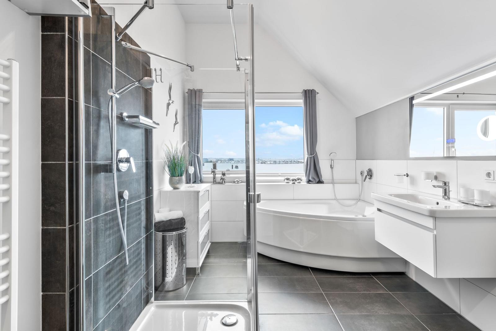 Badezimmer mit Dusche, Badewanne und Fensterblick auf Hafen