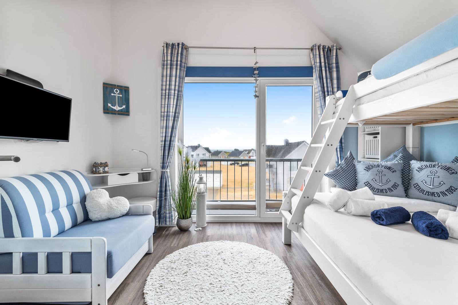 Schlafzimmer mit Doppelstockbett, Sofa und Balkon mit Meerblick.