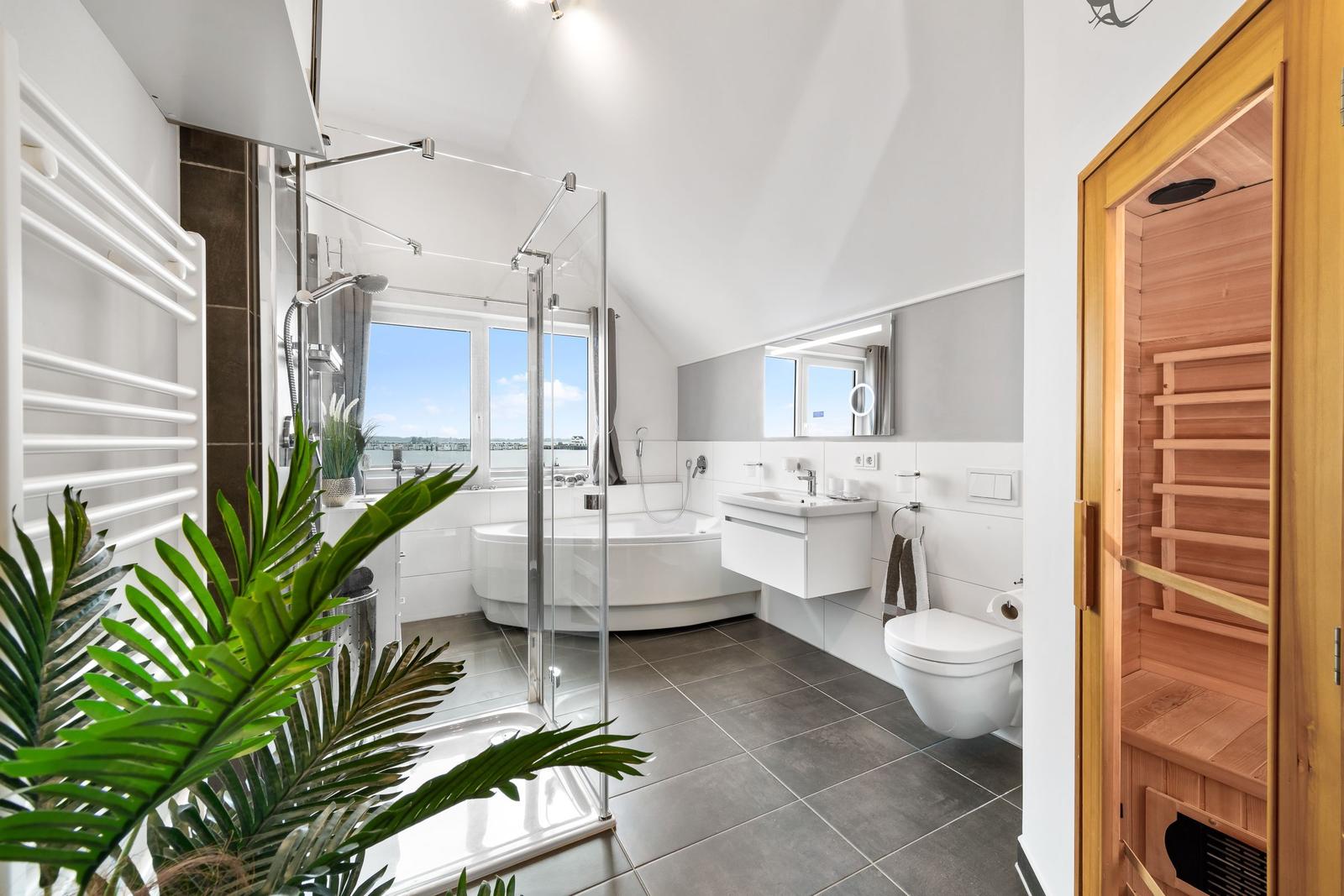 Badezimmer mit Badewanne, Dusche und Sauna. Große Fenster mit Meerblick.
