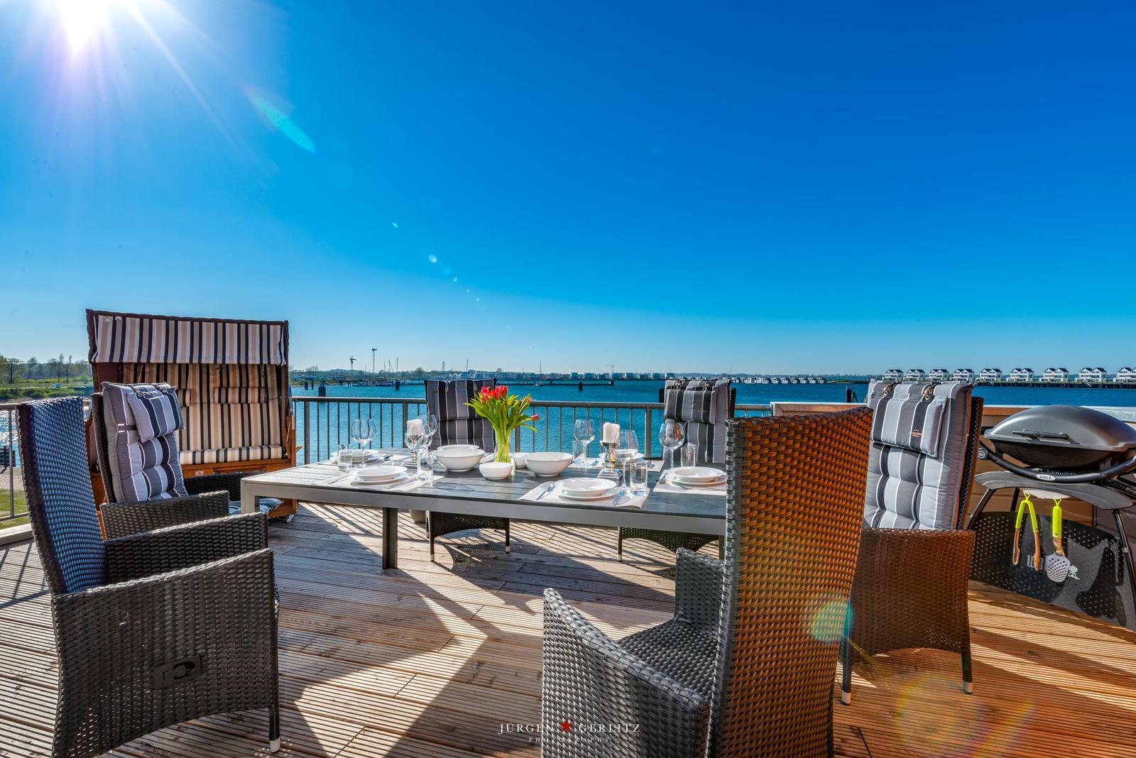 Terrasse mit Esstisch, Stühlen und Grill direkt am Wasser.