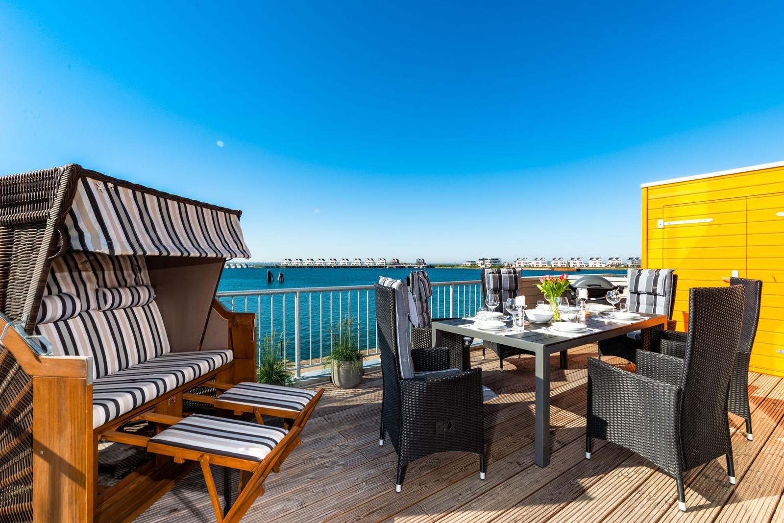 Terrasse mit Strandkorb, Esstisch und Meerblick.