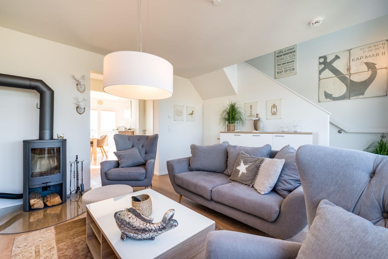 Wohnzimmer mit Sofa, Sessel und Kamin. Wanddekoration und Tisch mit Fischfigur.