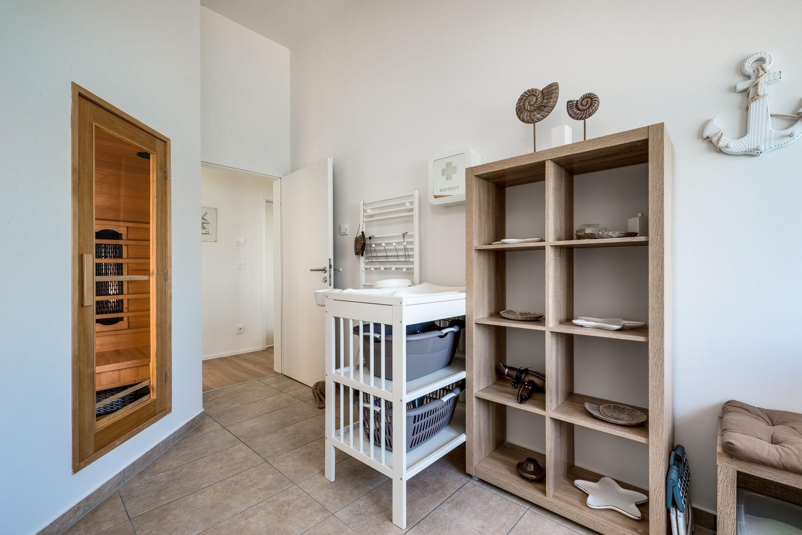 Sauna, Wickelstation und Regal mit Dekoration im Raum.